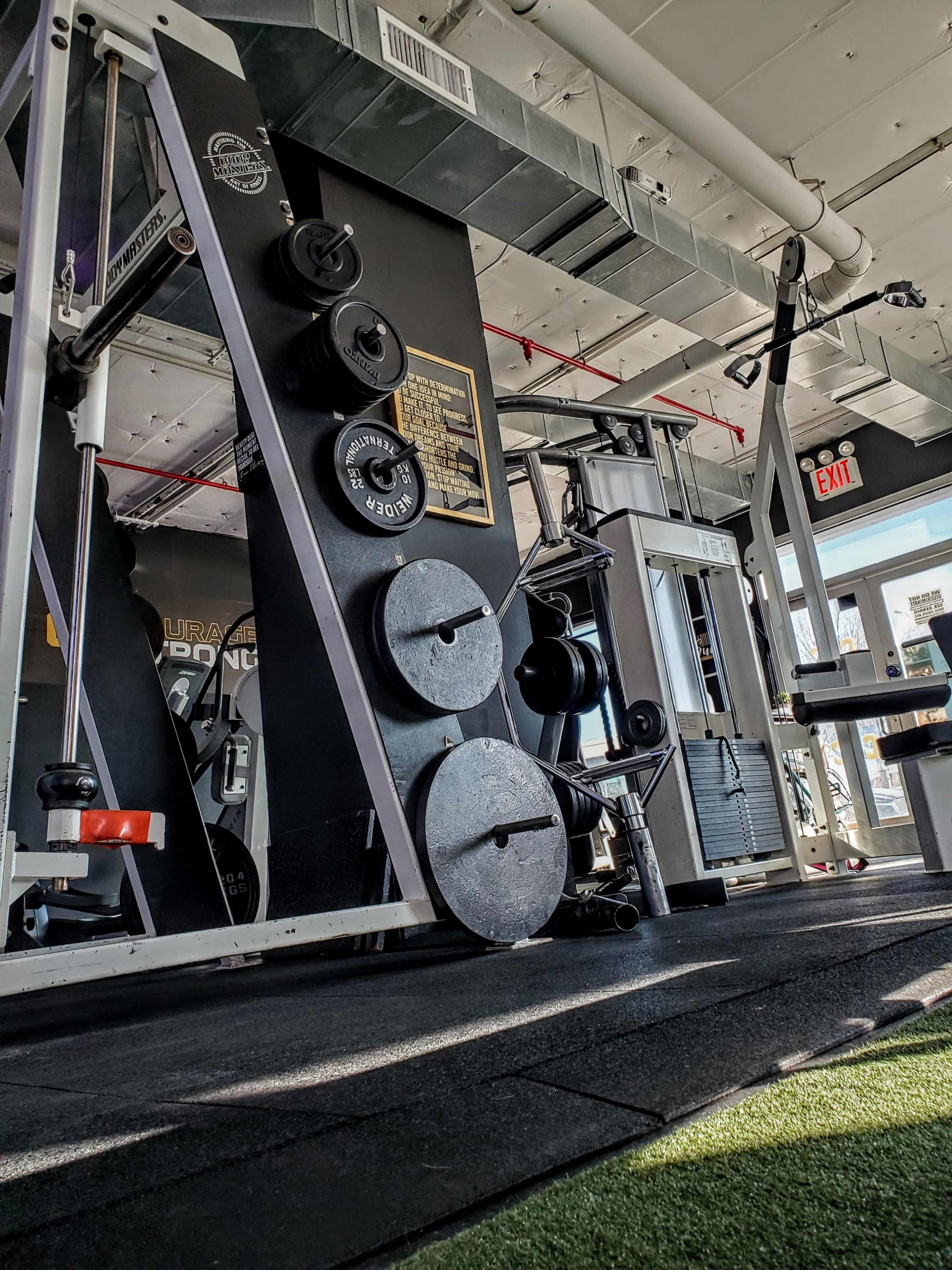 A well-equipped gym with various weightlifting machines and free weights arranged on the floor.
