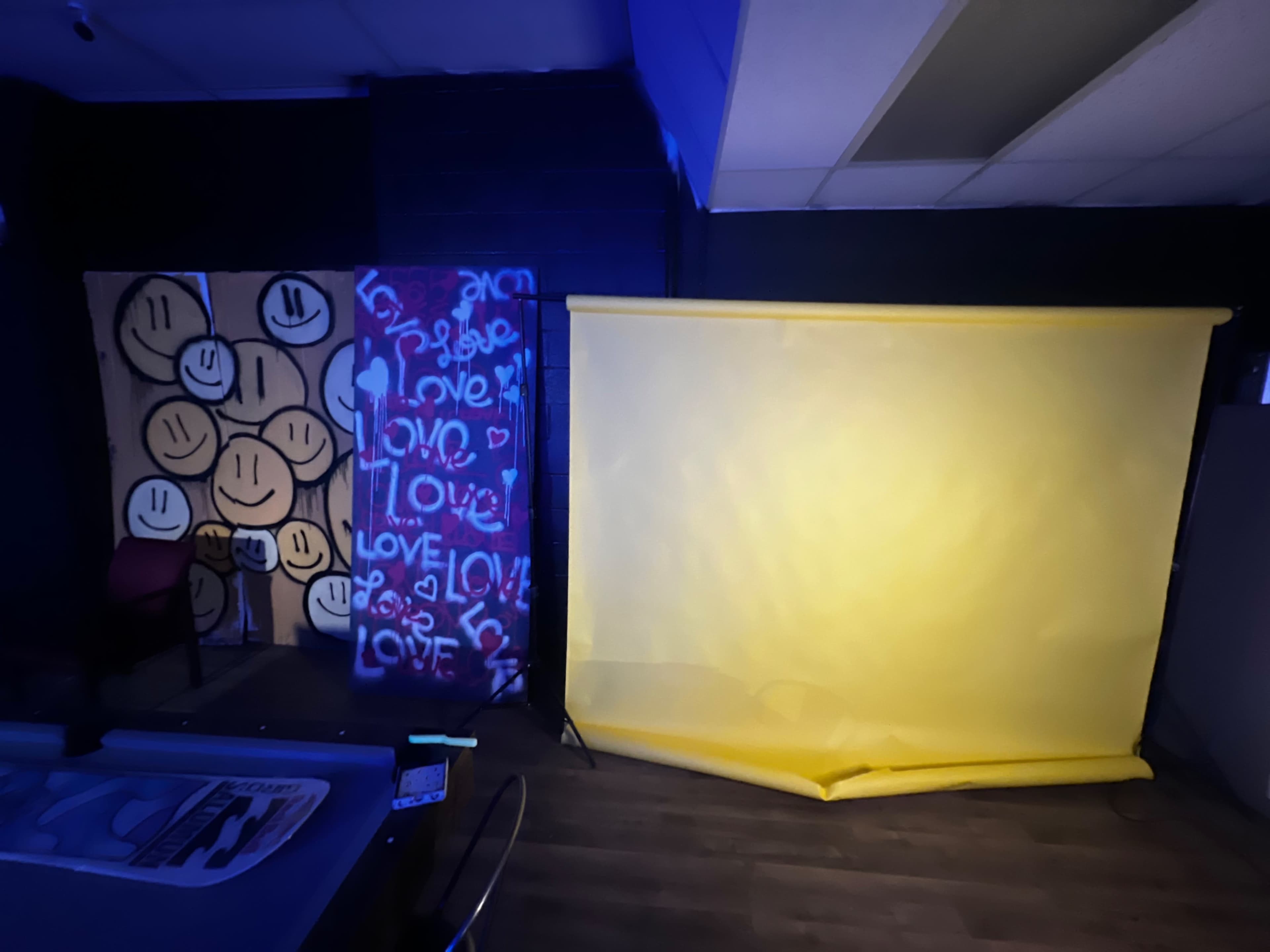 The scene shows a room with a yellow backdrop and a wall featuring various smiley faces and colorful graffiti that includes the word "love."