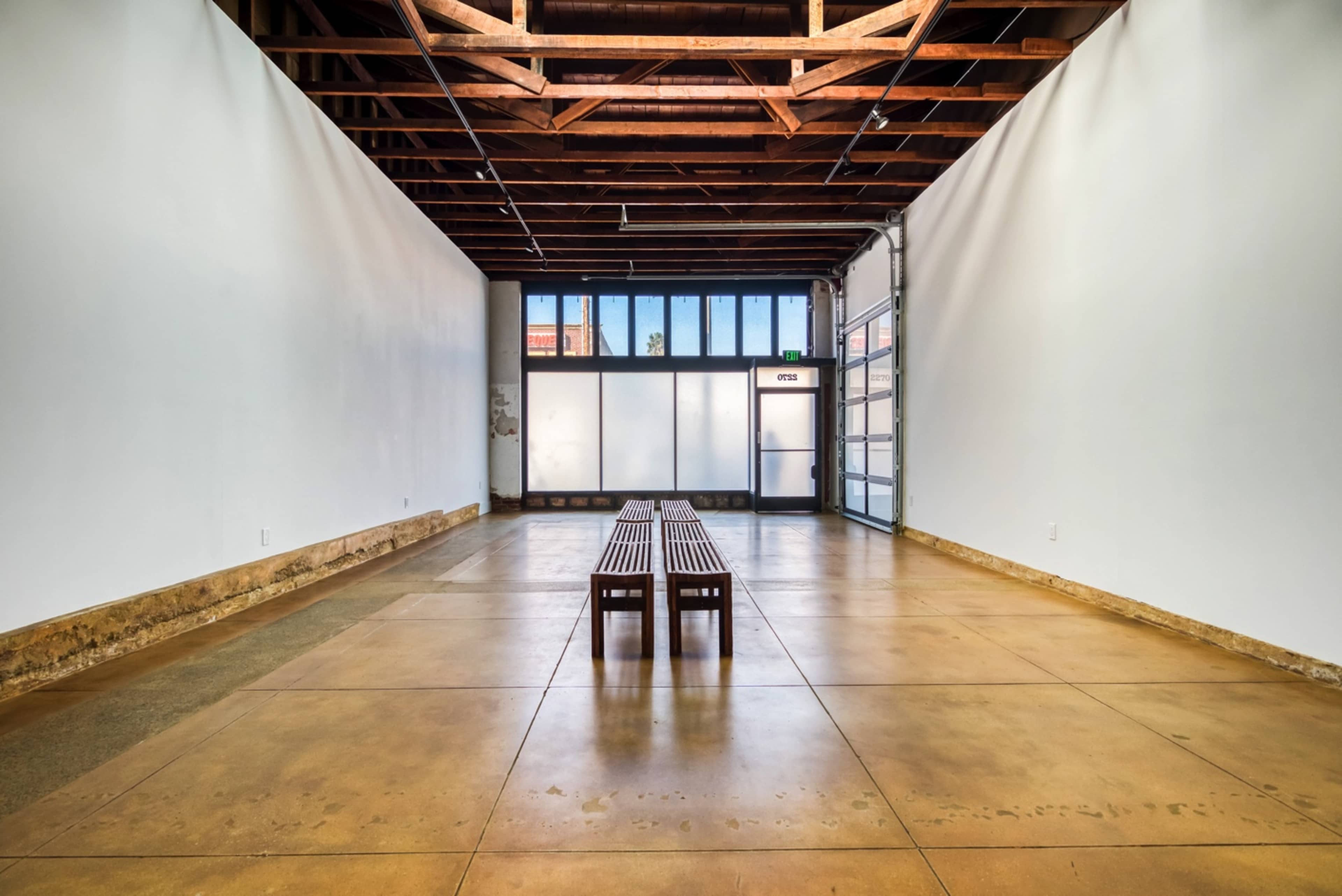 A spacious room with a wooden bench centered in front of large windows and a garage door.