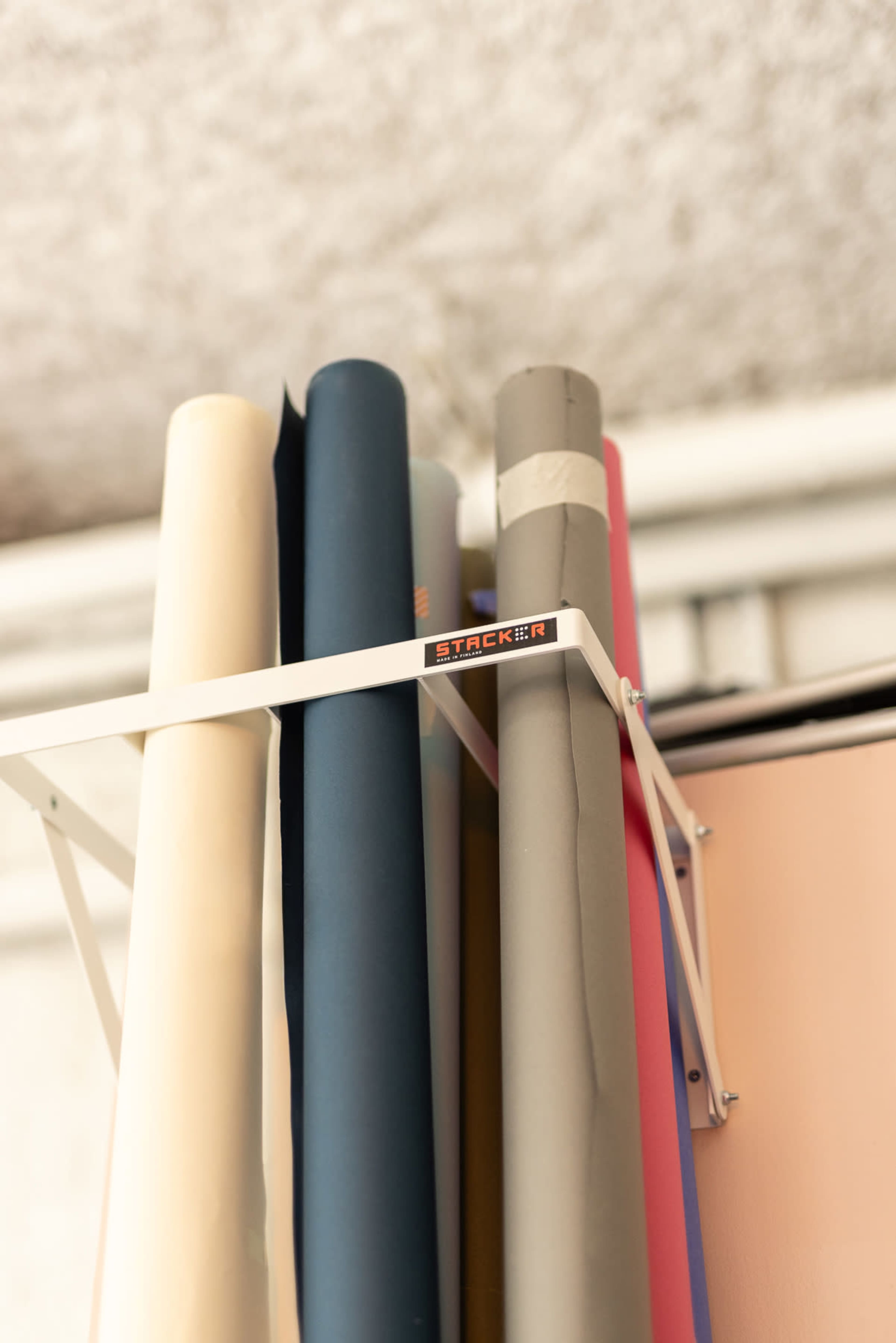 A metal rack holds several rolls of colored paper in various shades.