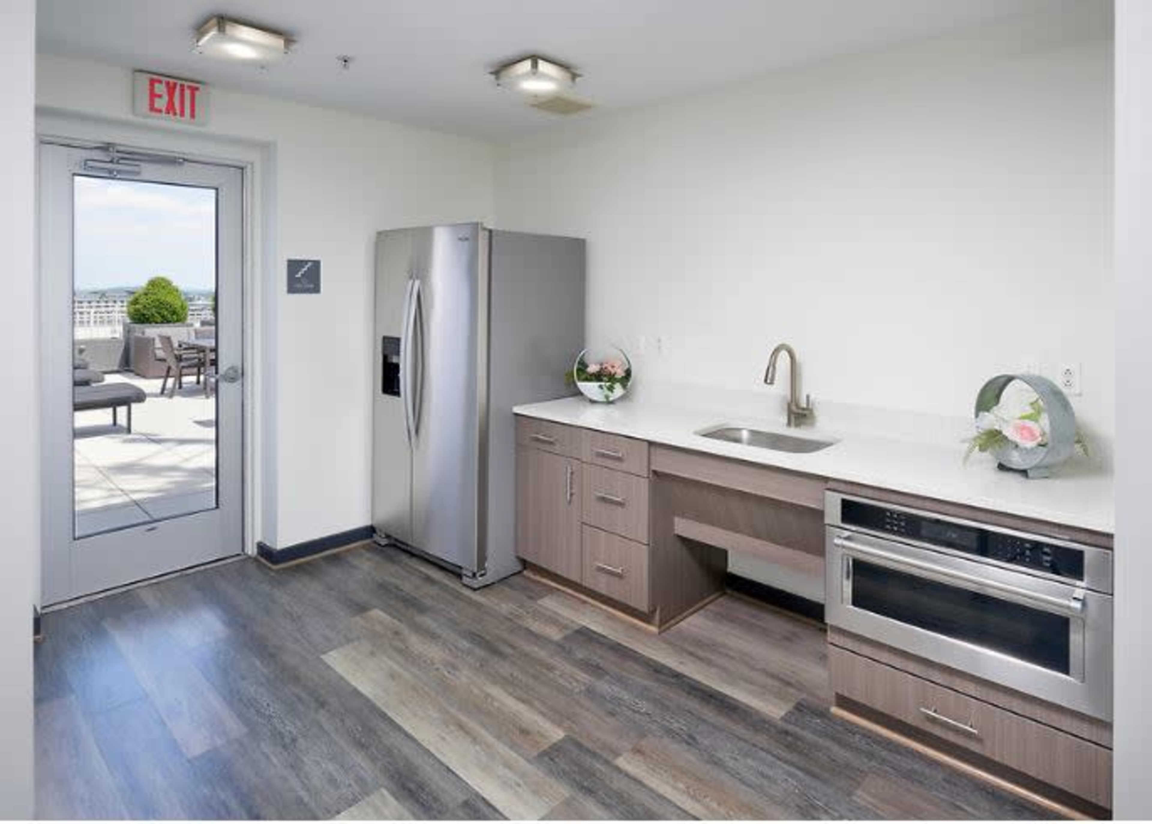 A modern kitchen with stainless steel appliances, including a refrigerator and wall oven, and a sink integrated into a spacious countertop.