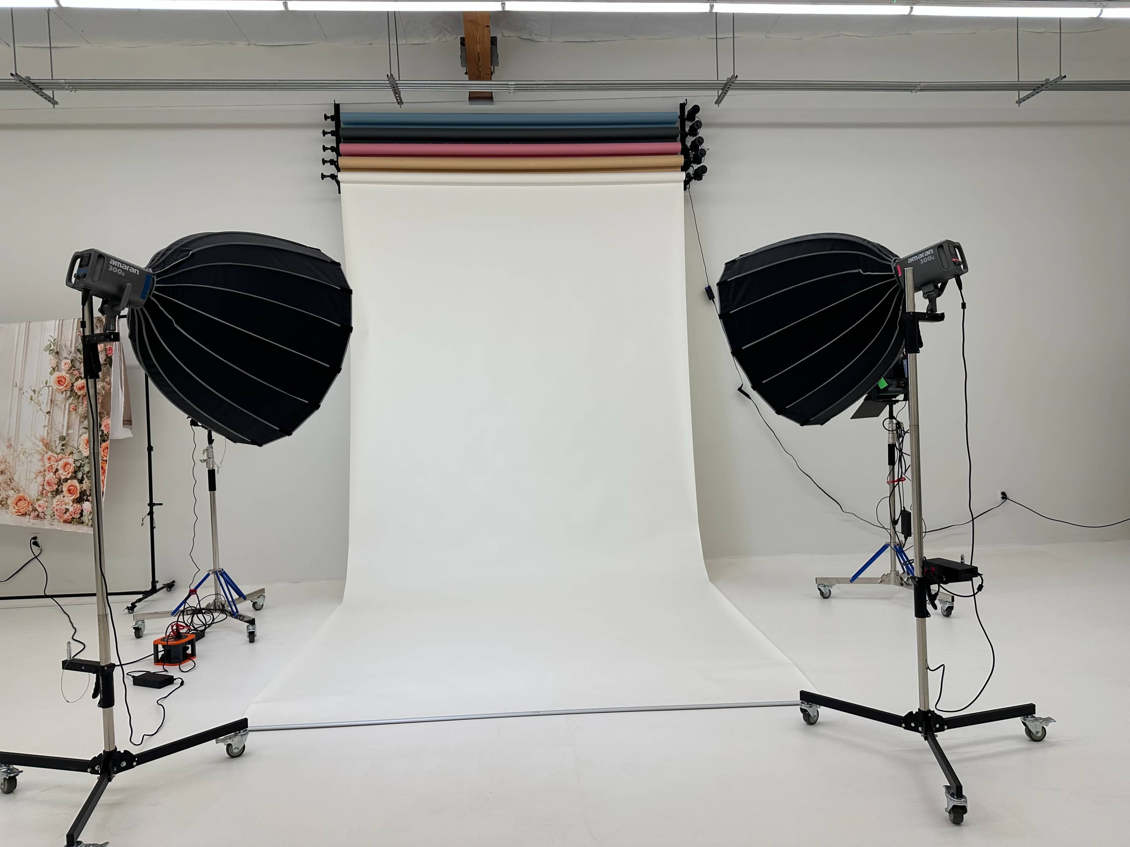 The image shows a photo studio setup with two large softbox lights positioned on either side of a white backdrop.