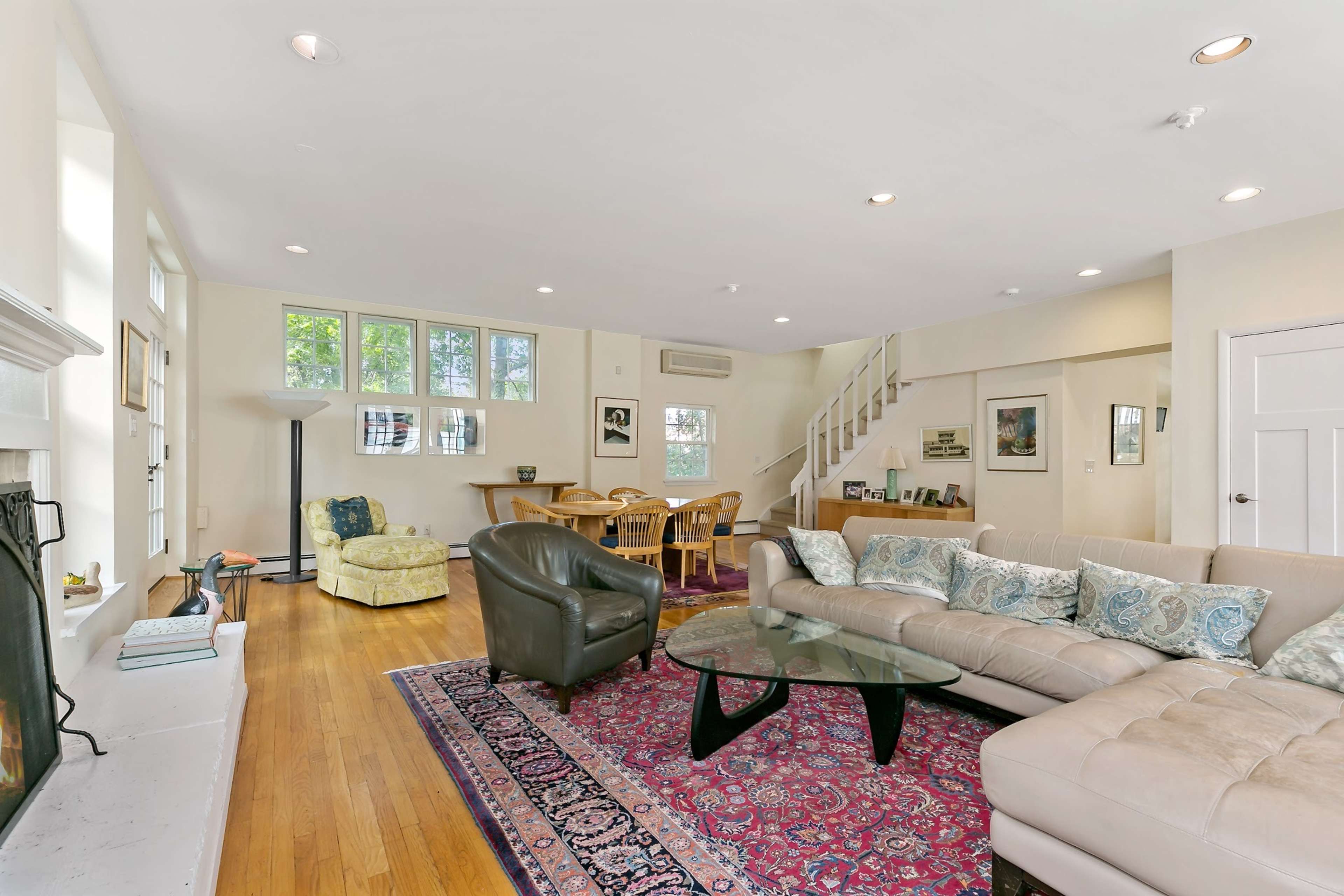 An open-concept living area with a sectional sofa, a glass coffee table, and a dining area adjacent to a staircase.