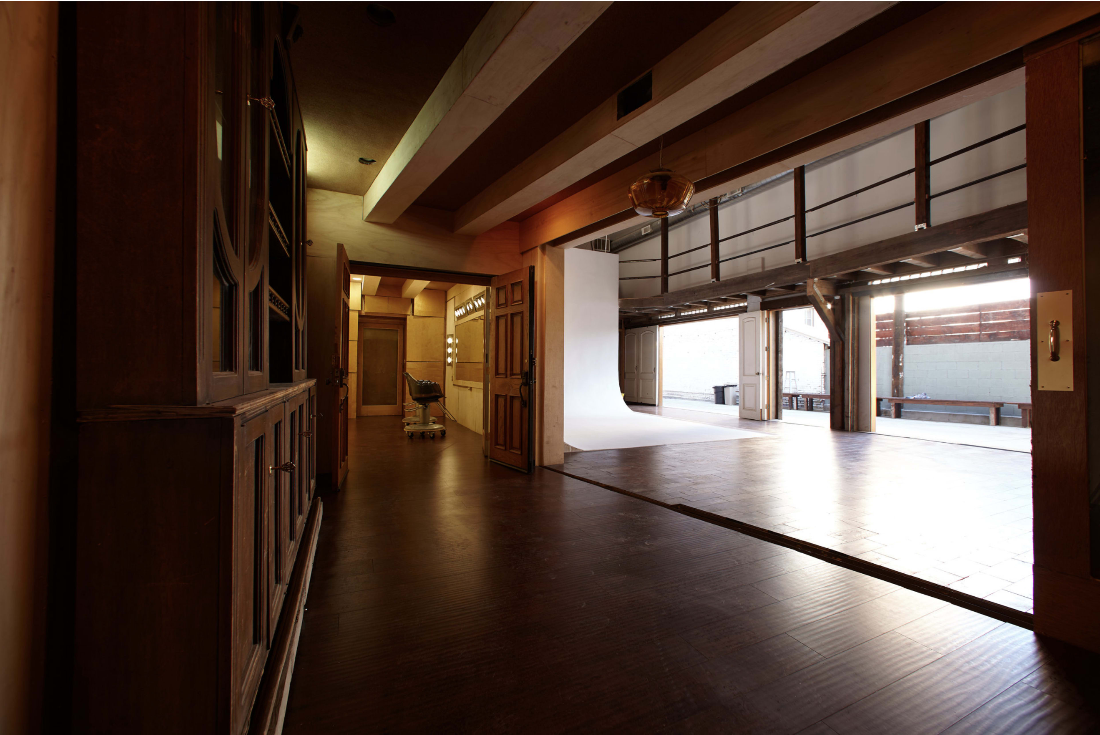A hallway leading to a spacious, well-lit area with a white backdrop and wooden flooring.