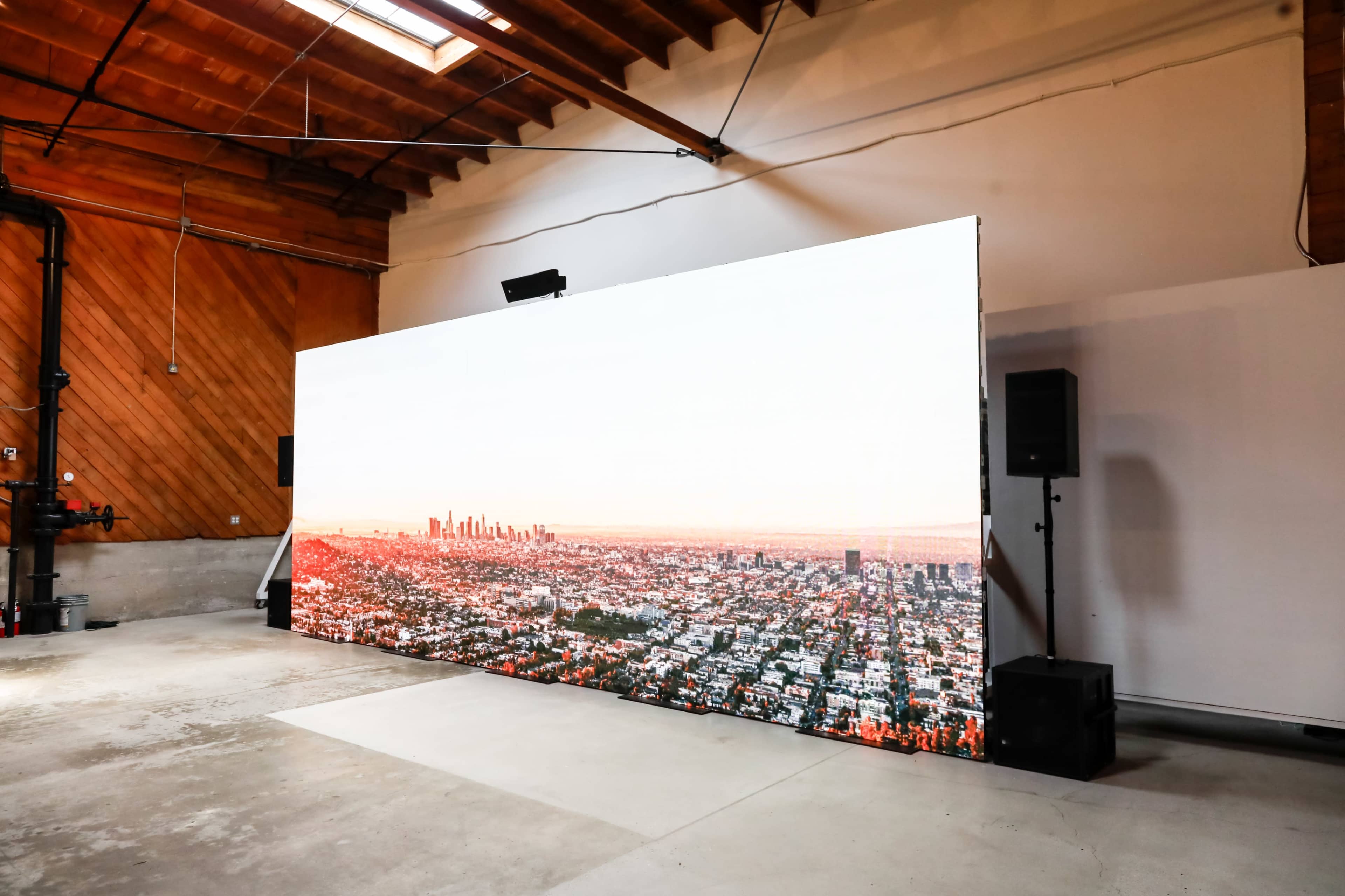 A large digital screen displaying a panoramic view of a city skyline is positioned against a wall in a spacious room.