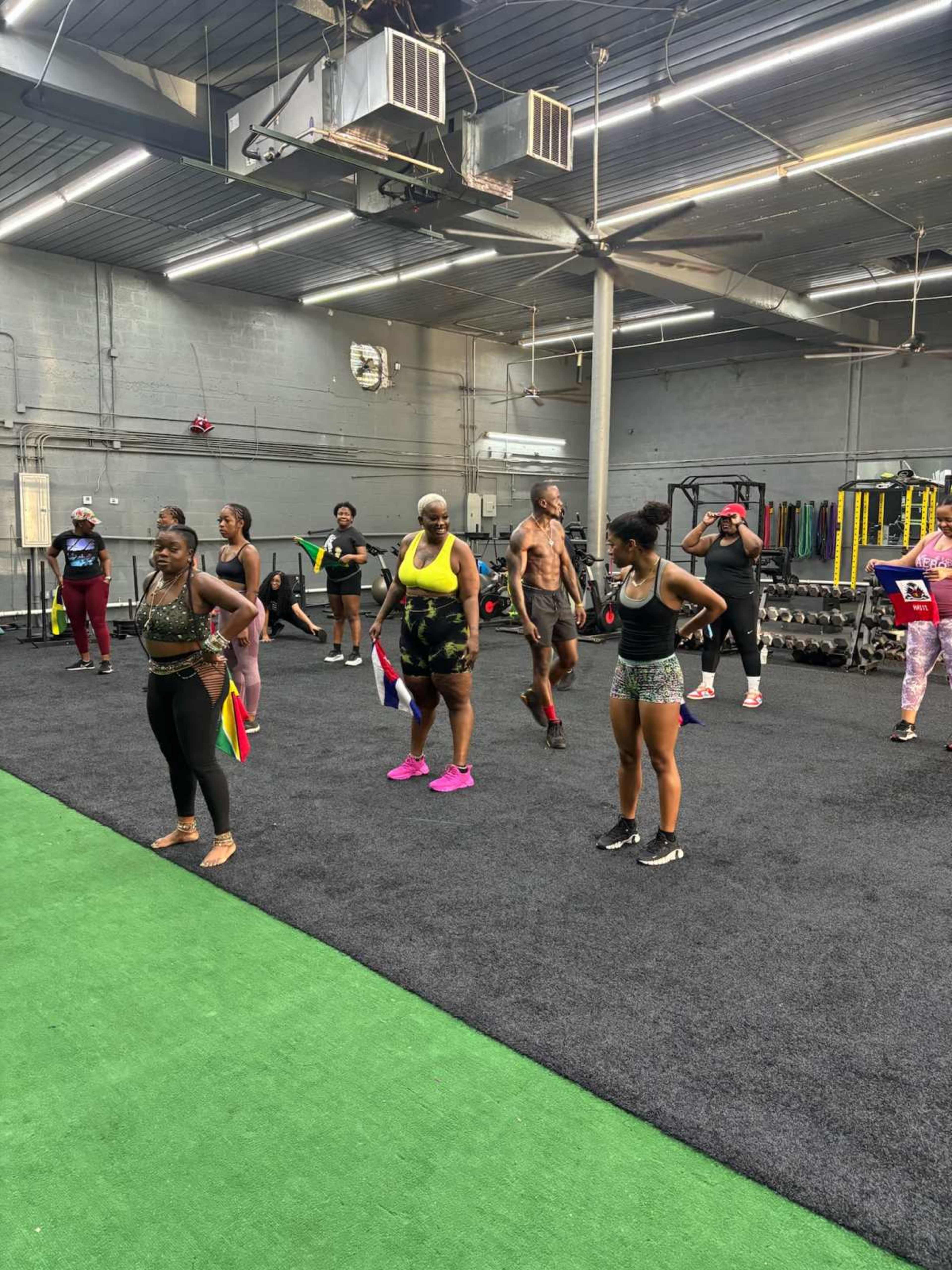 A group of individuals is participating in a fitness class inside a gym with exercise equipment in the background.
