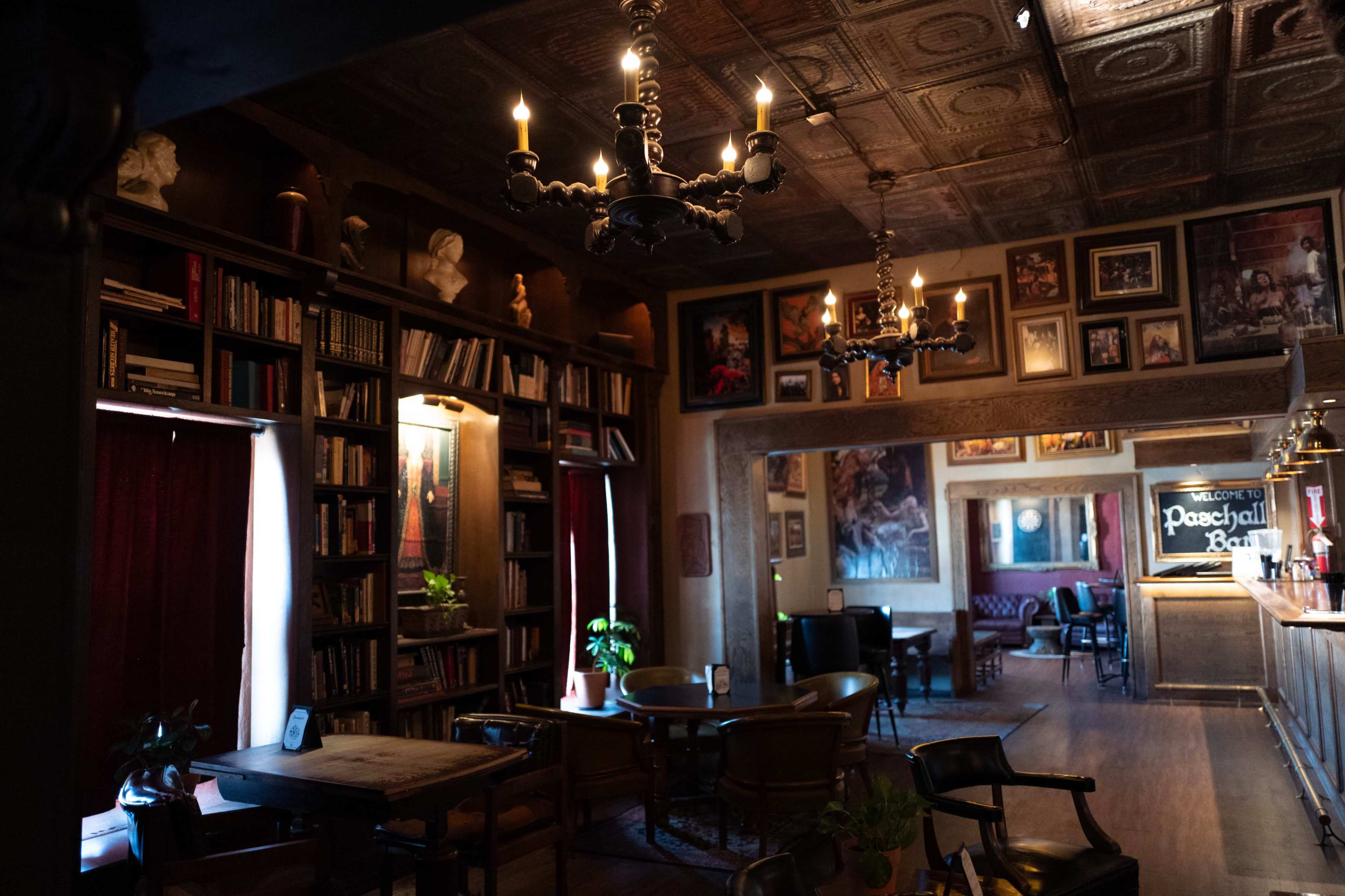 The image shows a dimly lit room with bookshelves, vintage furniture, and decorative wall art, creating an inviting atmosphere.