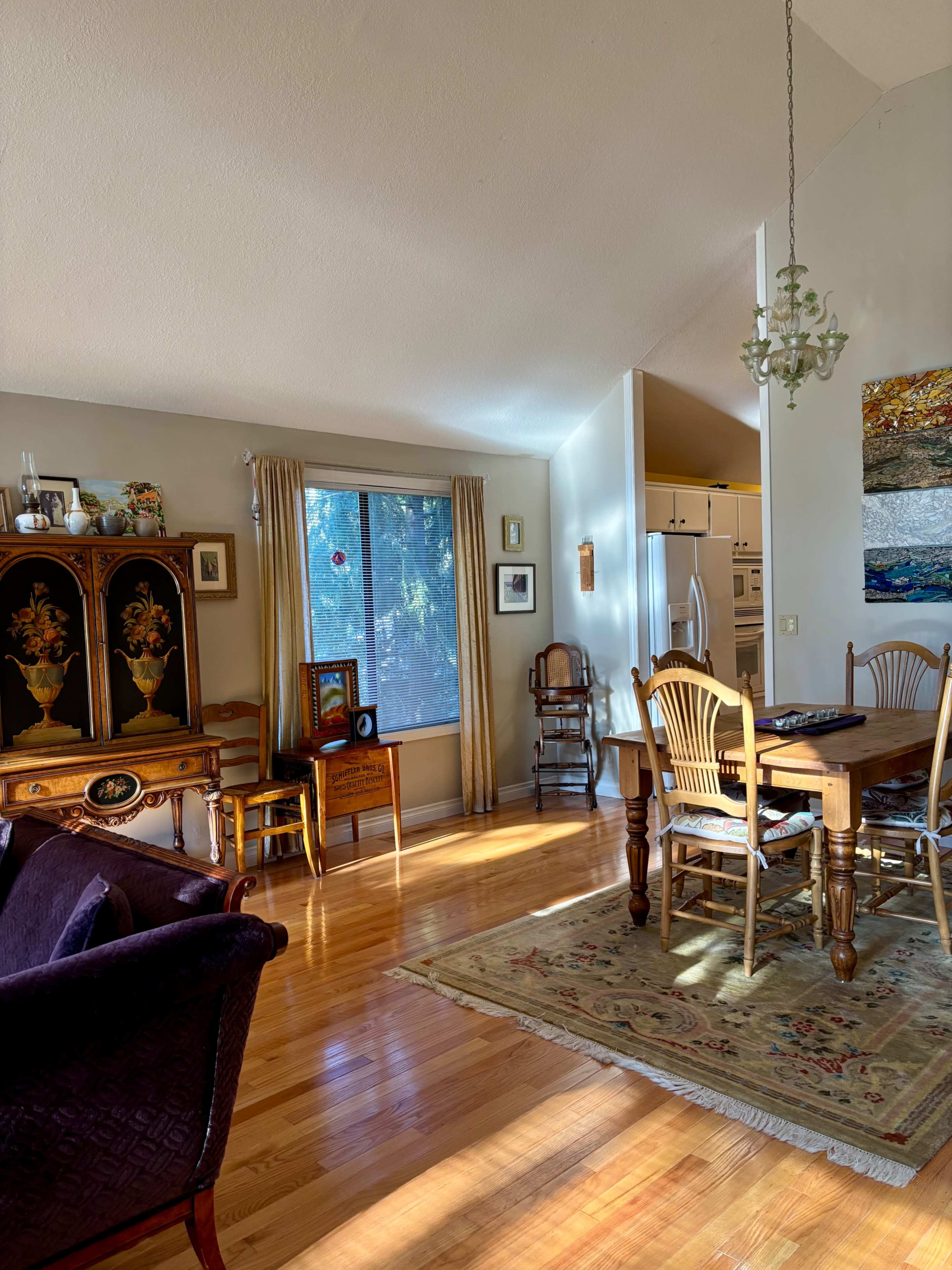 A cozy dining area features a wooden table surrounded by chairs, with a window providing natural light and a view of the outdoors.