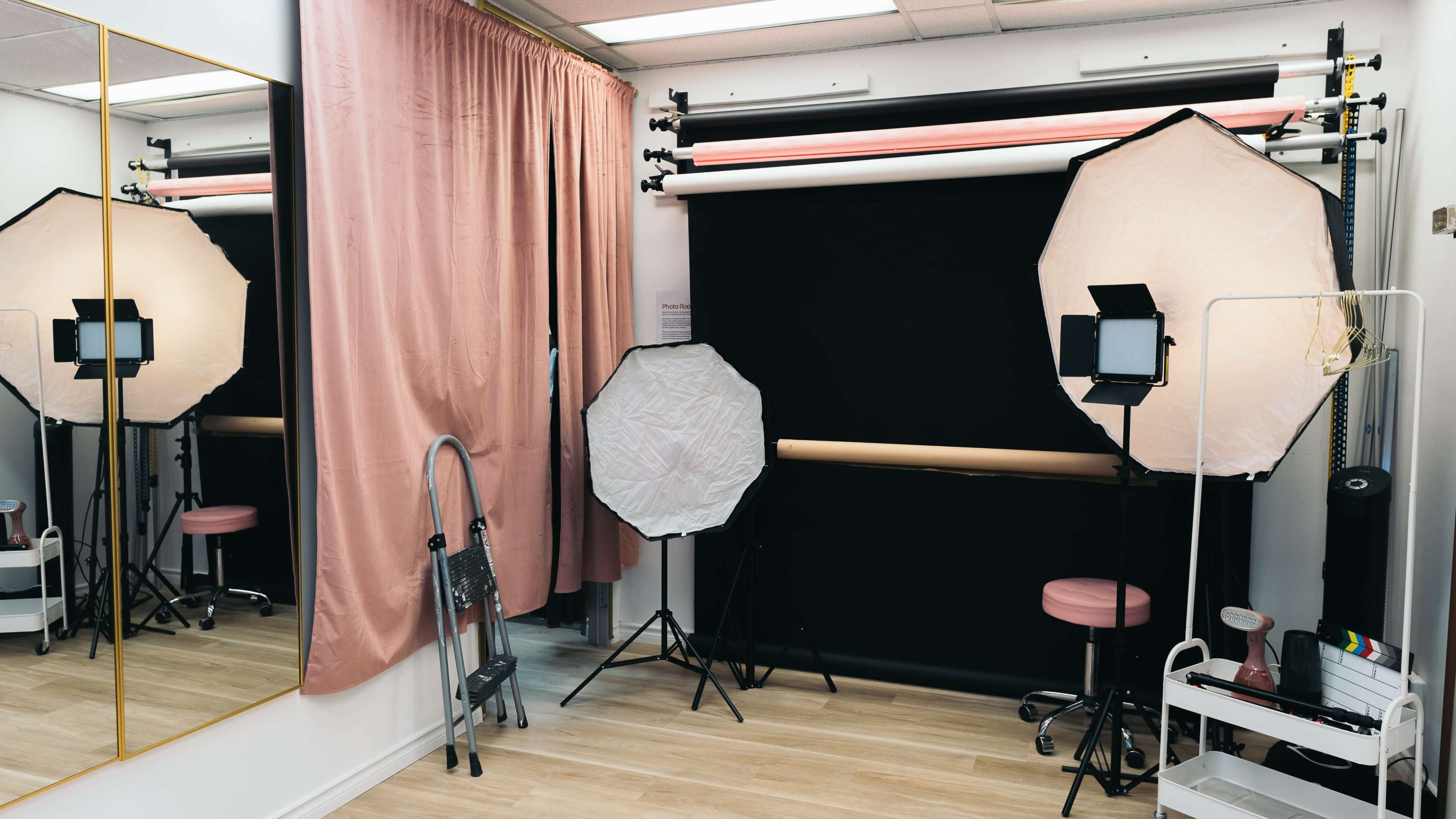 The image shows a photography studio with softboxes, a backdrop, and a mirror, arranged in a well-lit space.