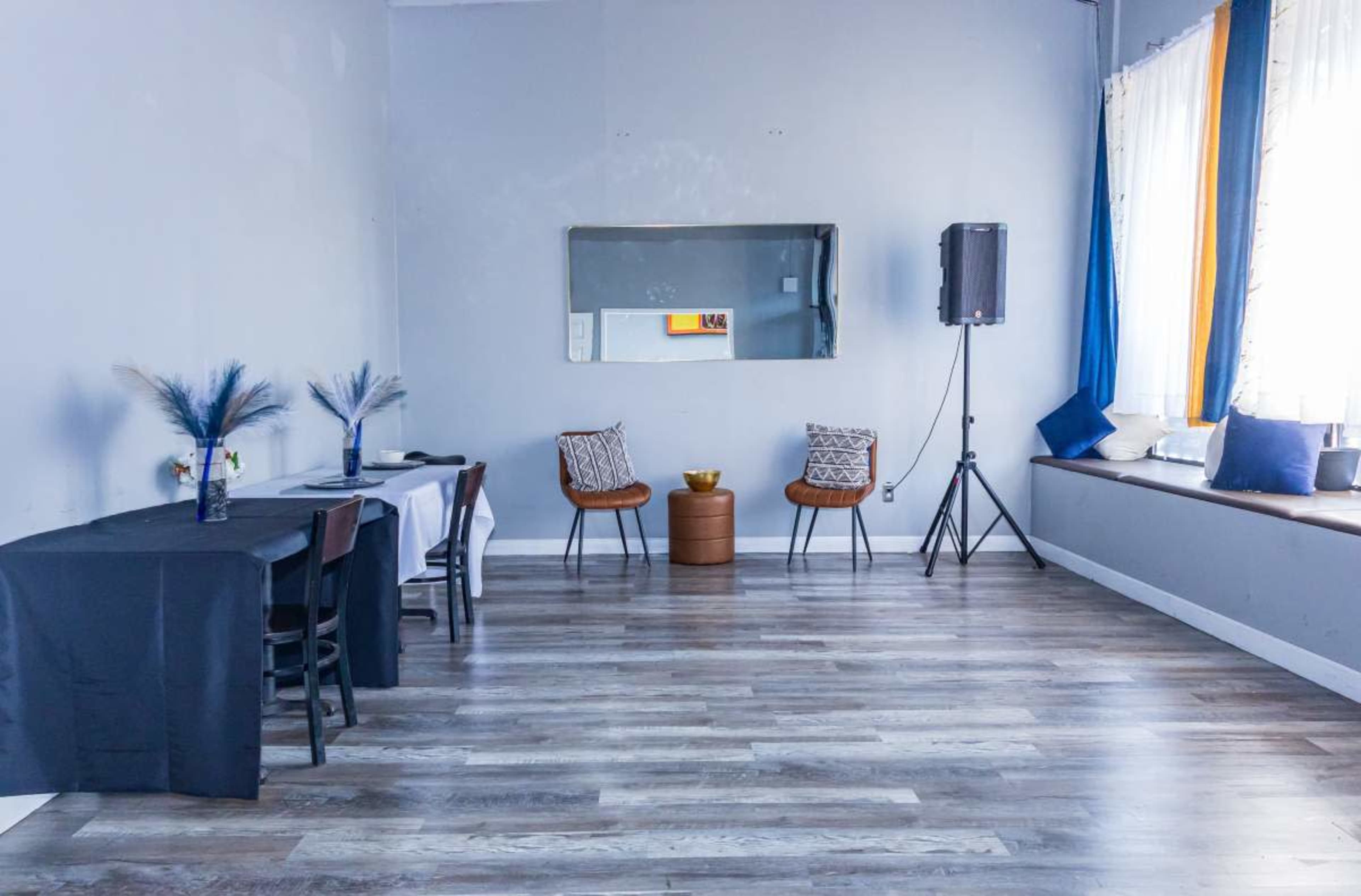 The image shows a modern, empty room with two chairs, a small table, and a mirror on the wall.