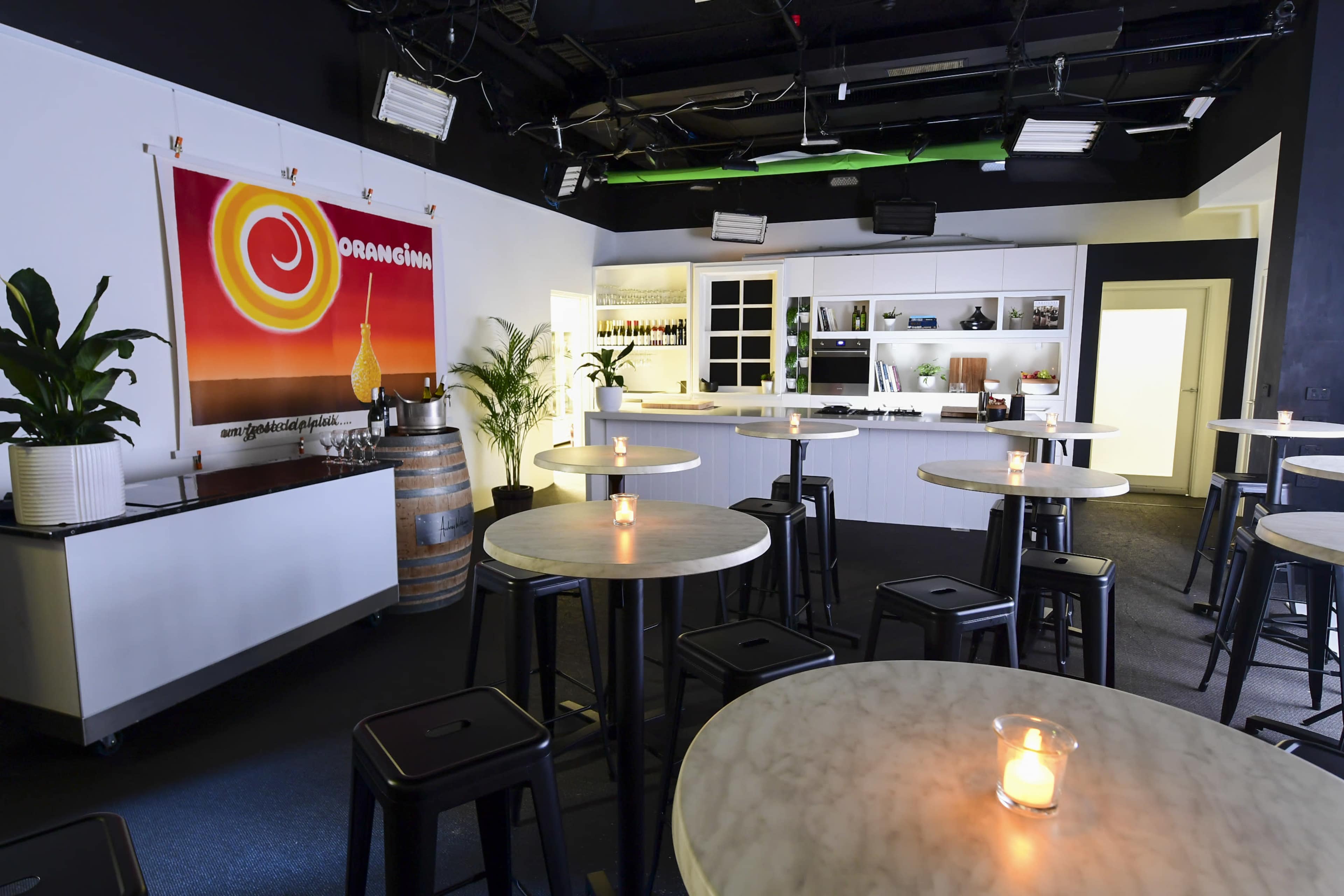 A spacious, modern bar with marble tables, black chairs, and a large orange-themed mural on the wall.