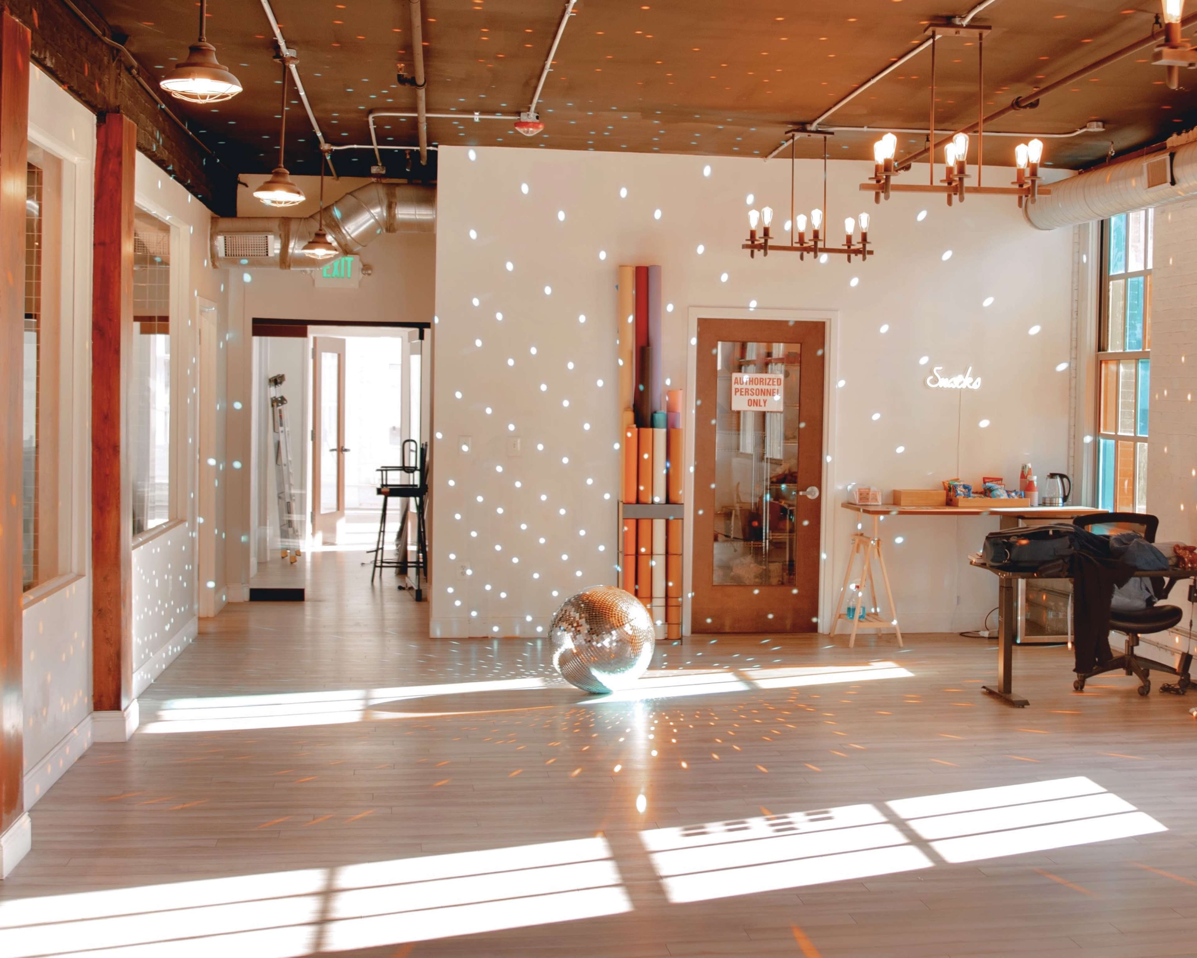 The room features a large disco ball reflecting light spots across the walls and floor, with various furniture and an open layout.