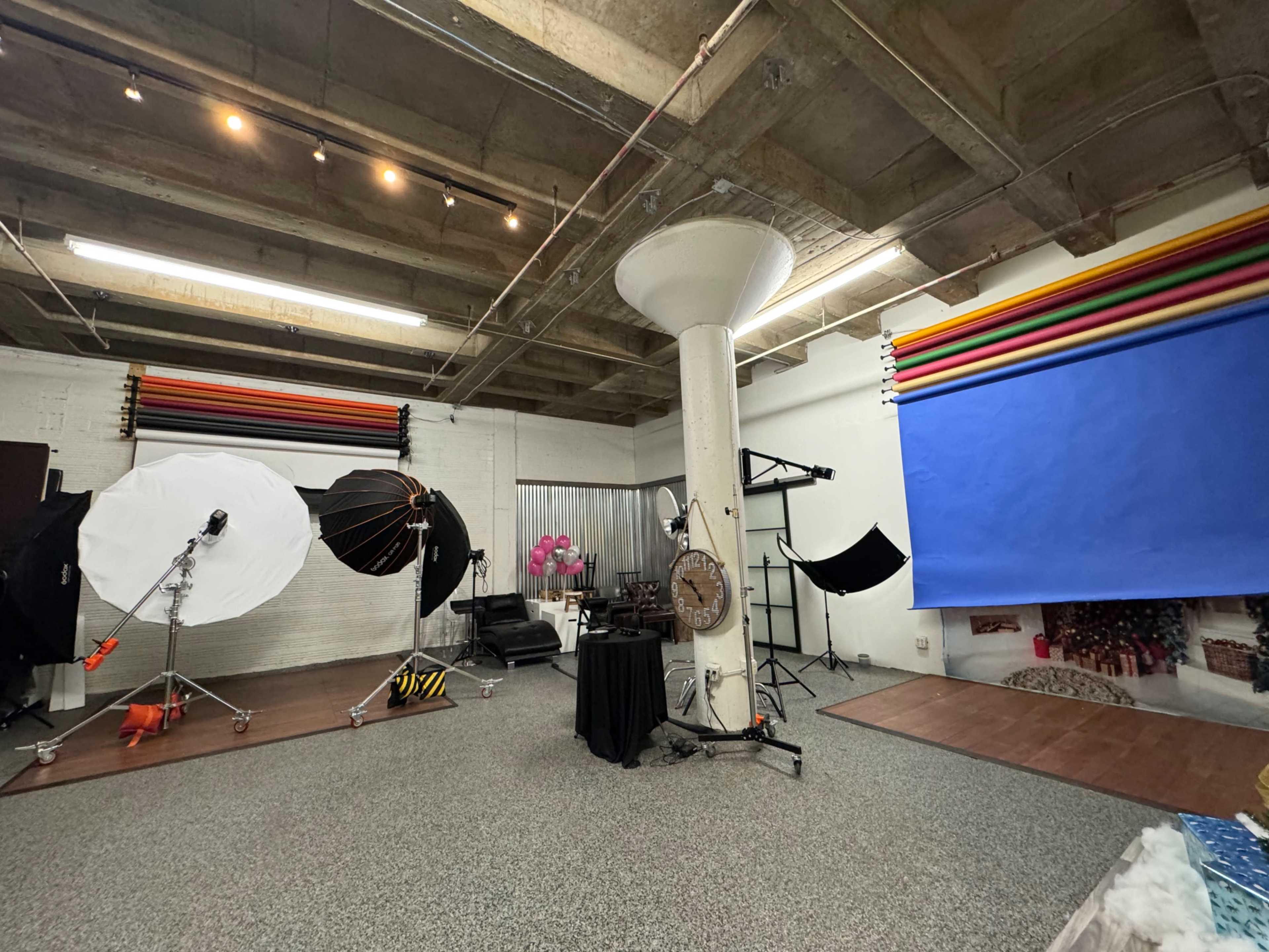 A photography studio with various lighting equipment, backdrops, and props arranged around a spacious area.