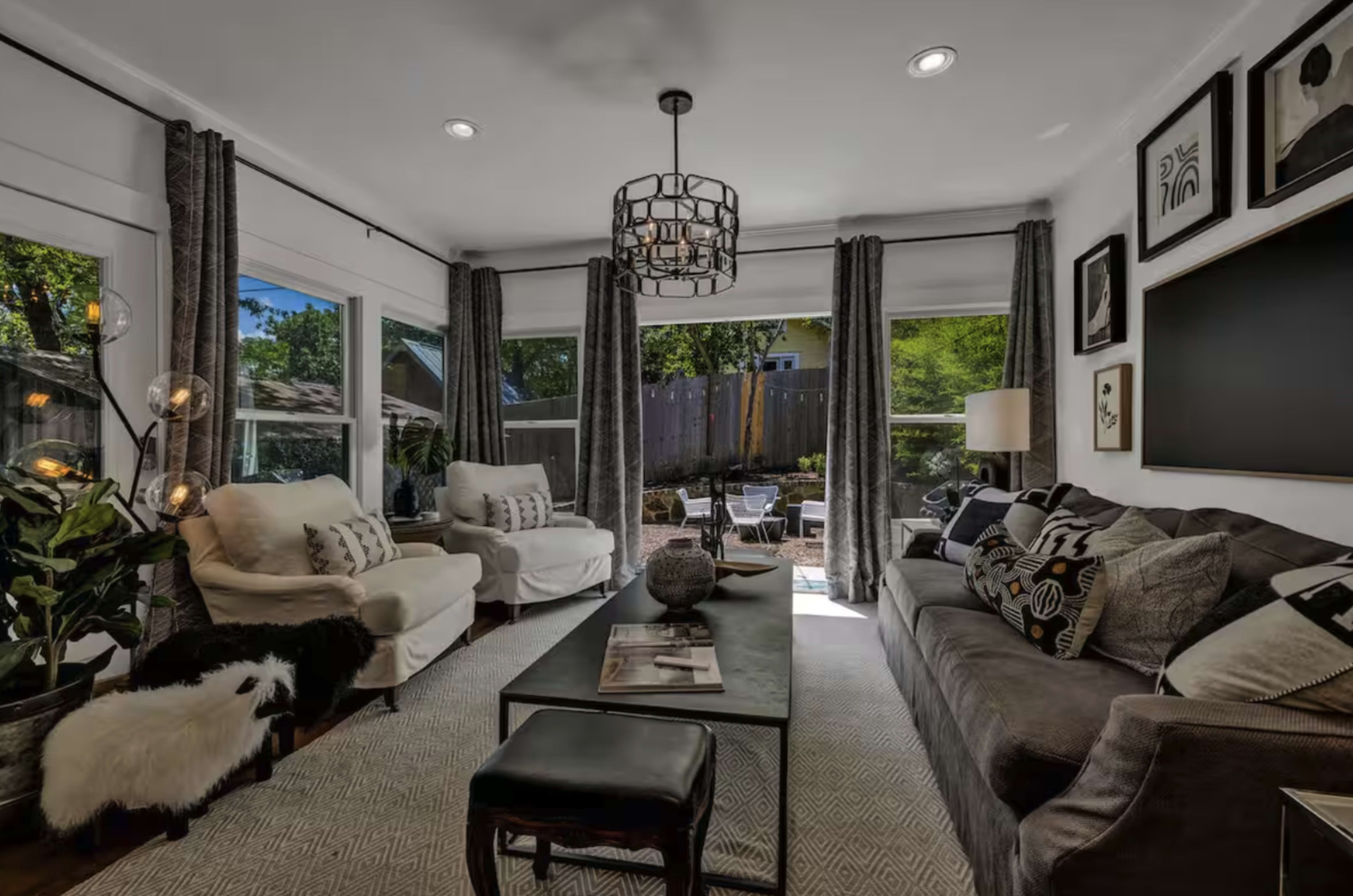 The living room features two sofas, a coffee table, and large windows that provide a view of an outdoor space.