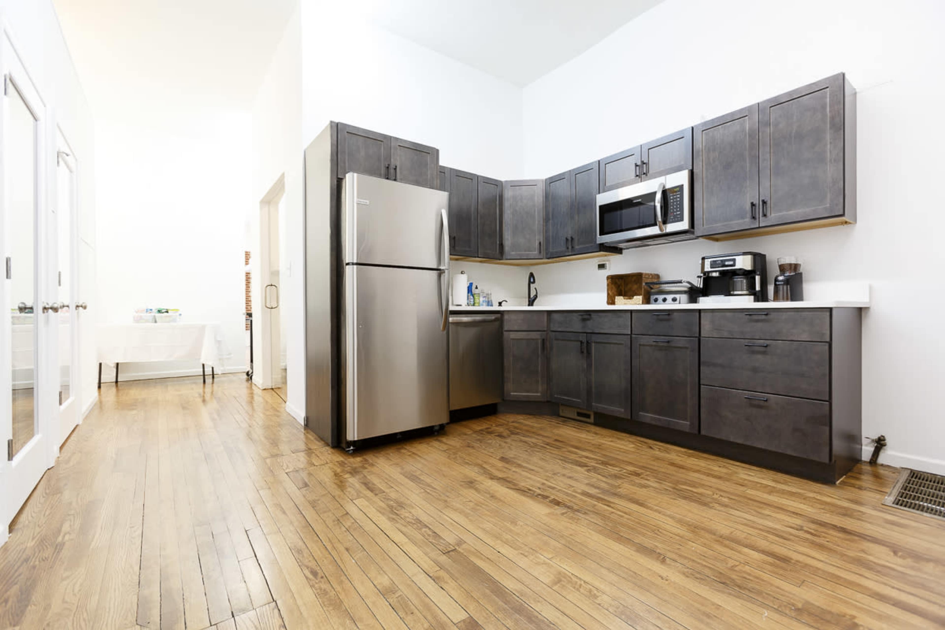 A modern kitchen with dark wooden cabinets, stainless steel appliances, and hardwood floors.