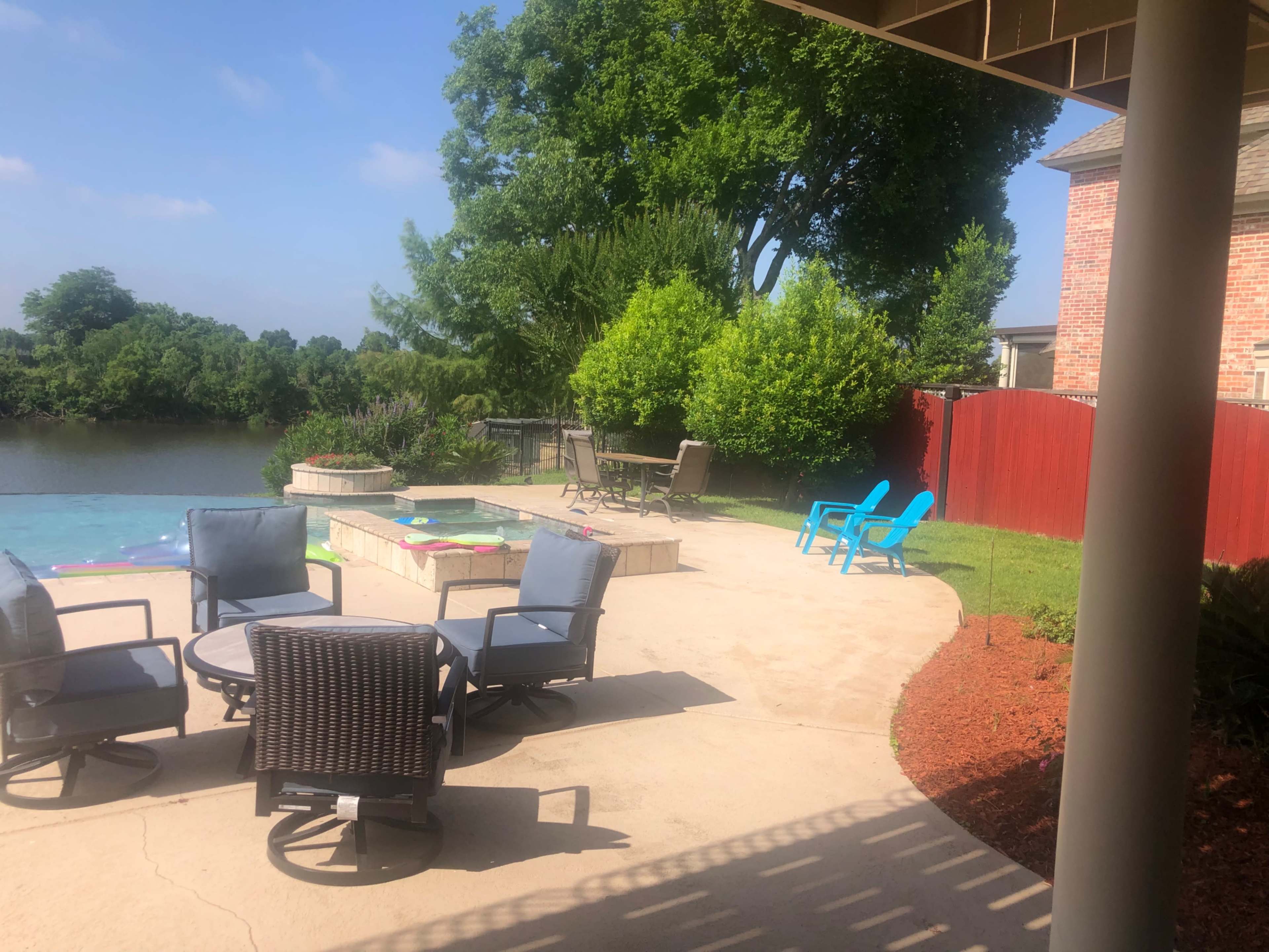 A backyard with patio furniture, a swimming pool, and a scenic view of a body of water and greenery.