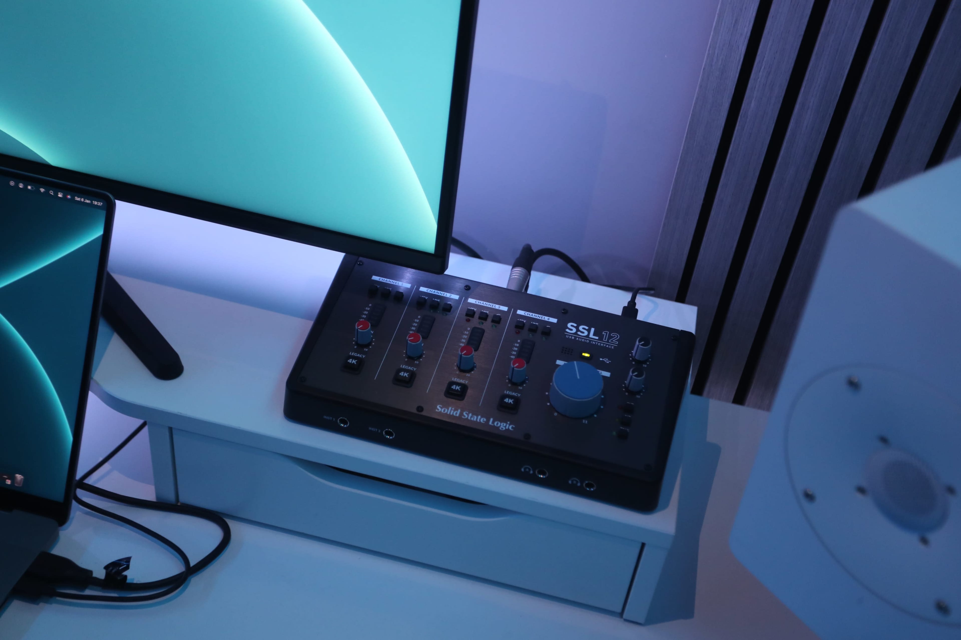 A Solid State Logic audio interface is placed on a white desk next to a computer monitor.
