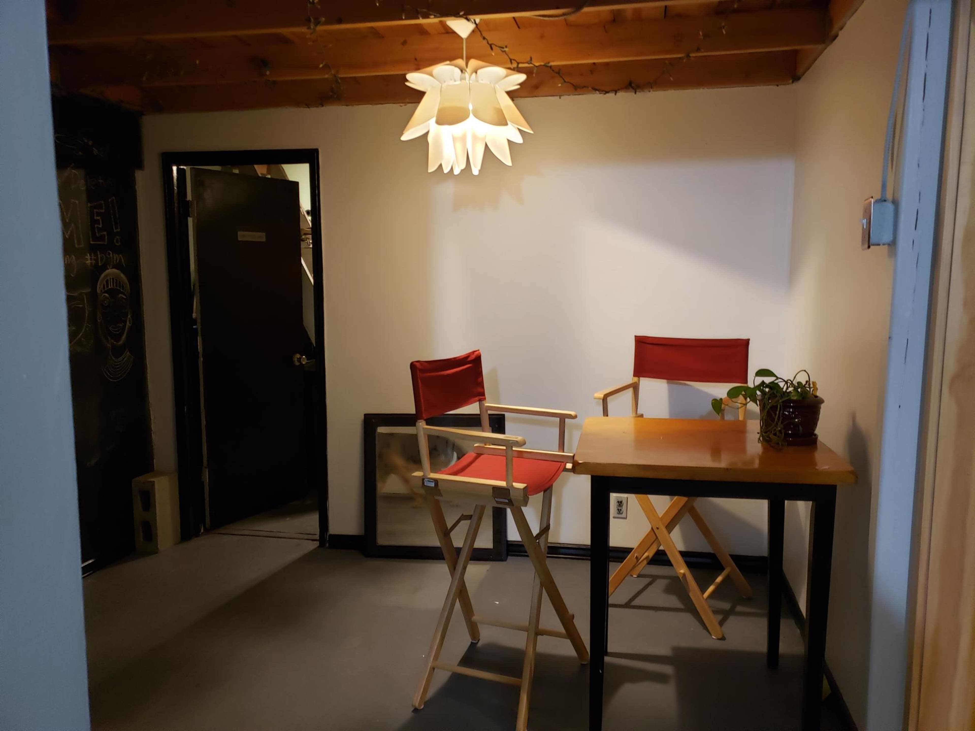 The scene shows a small room with a table, two chairs, a plant, and a pendant light hanging from the ceiling.