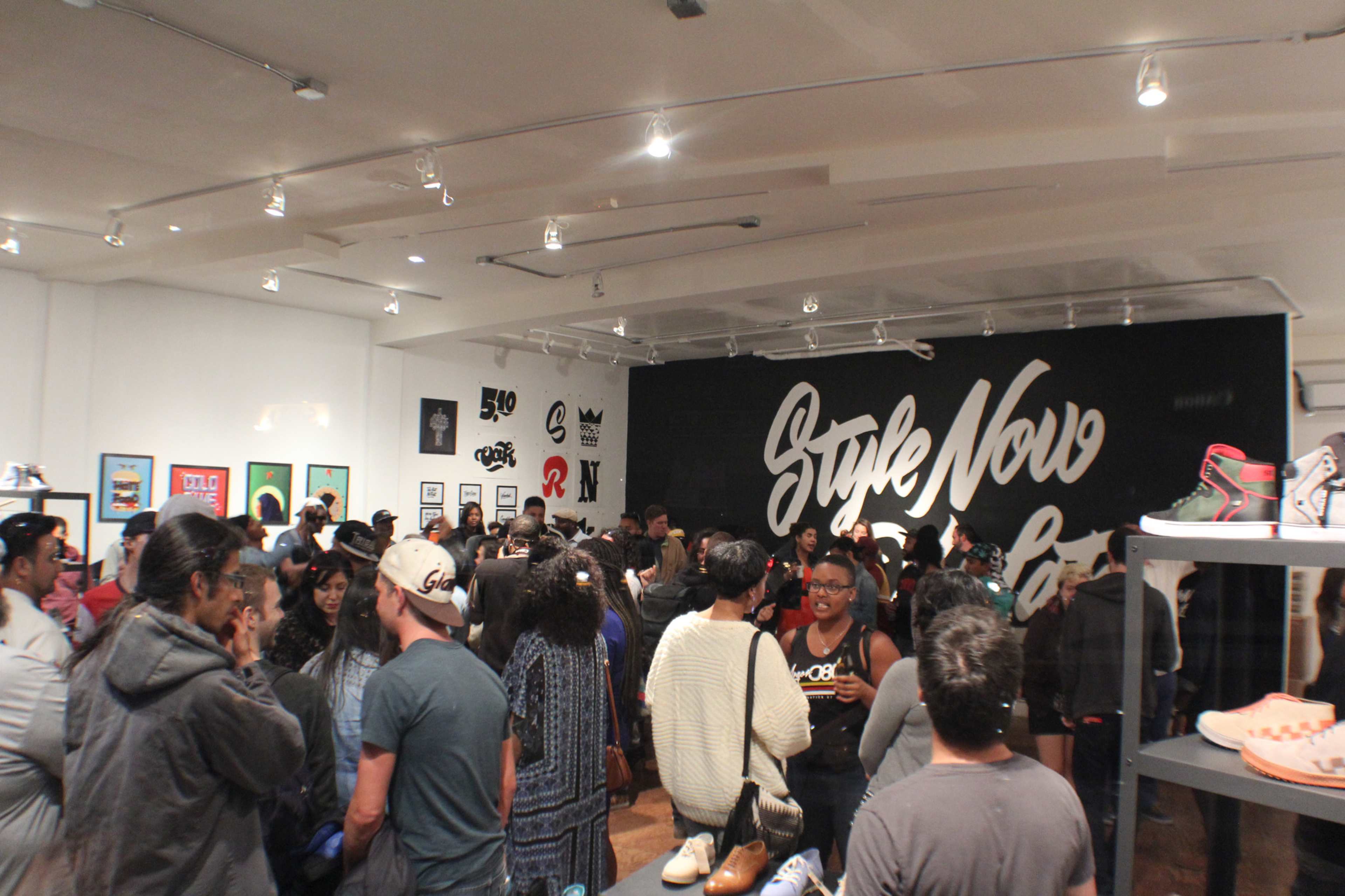 A large crowd of people gathers in a sneaker store with prominent wall art that reads "Style Now."