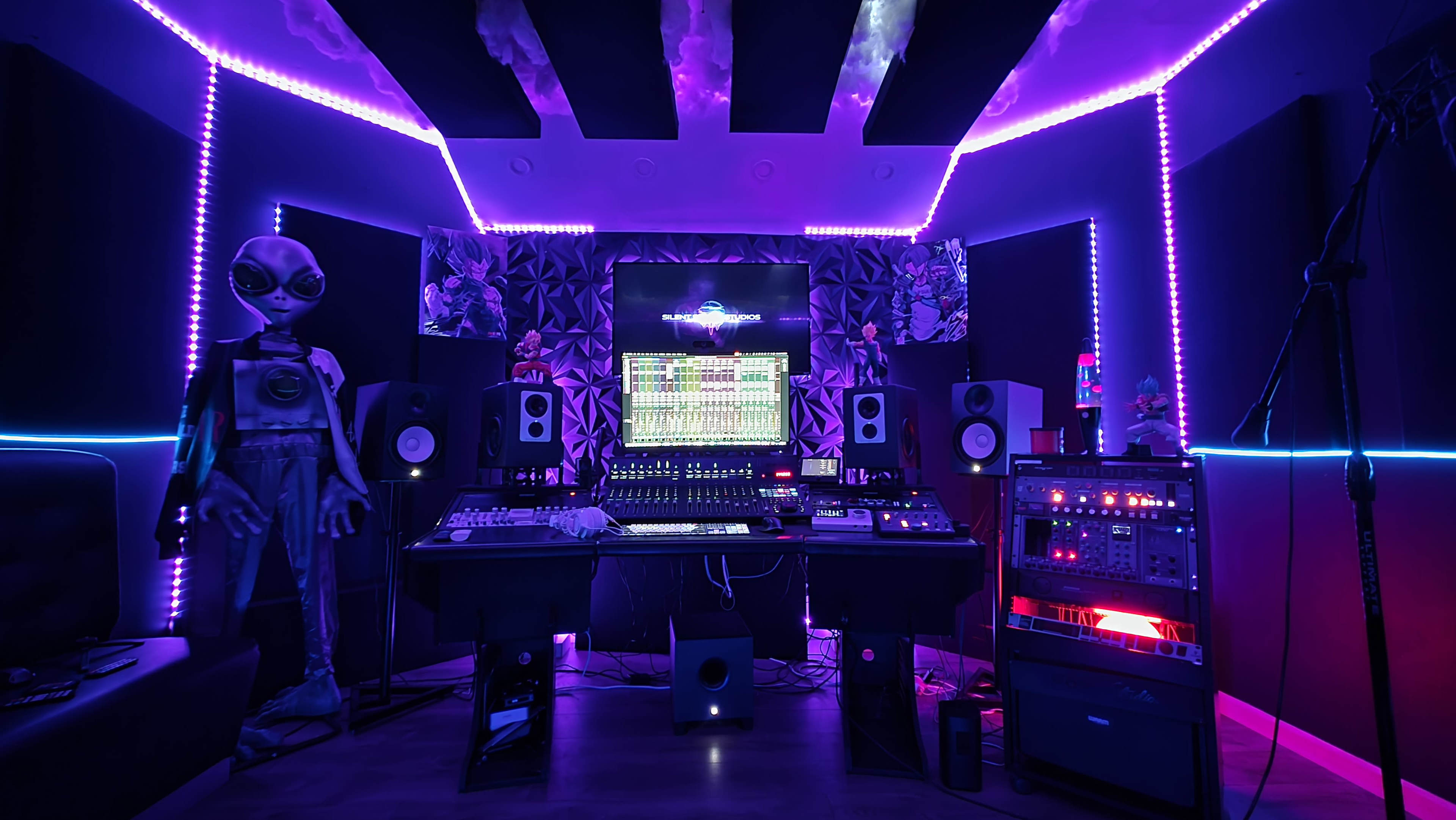 The image shows a music studio with colorful LED lighting, featuring a mixing console, speakers, and an alien figure in the corner.