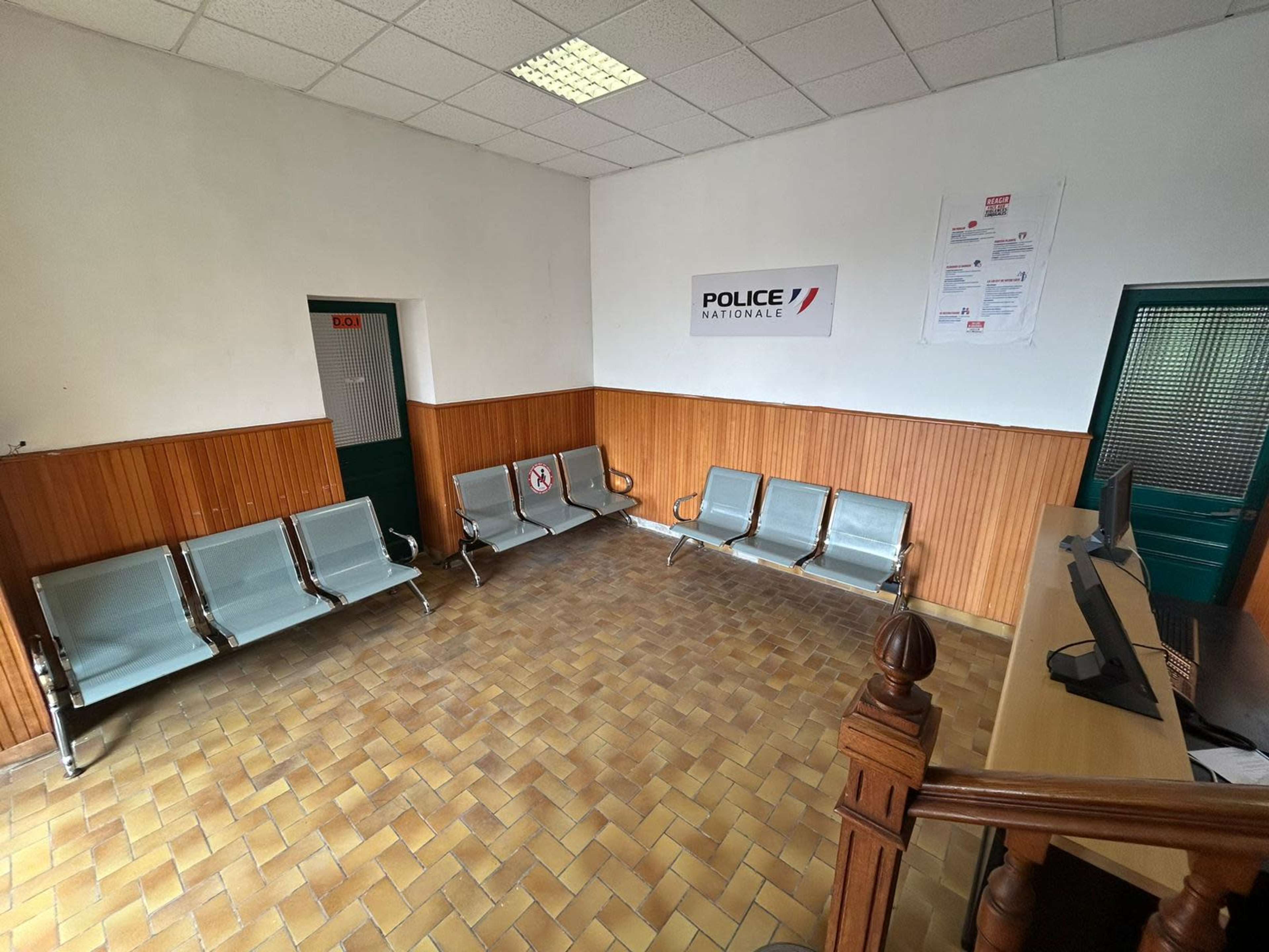 A waiting area in a police station with several metal benches and a reception desk.