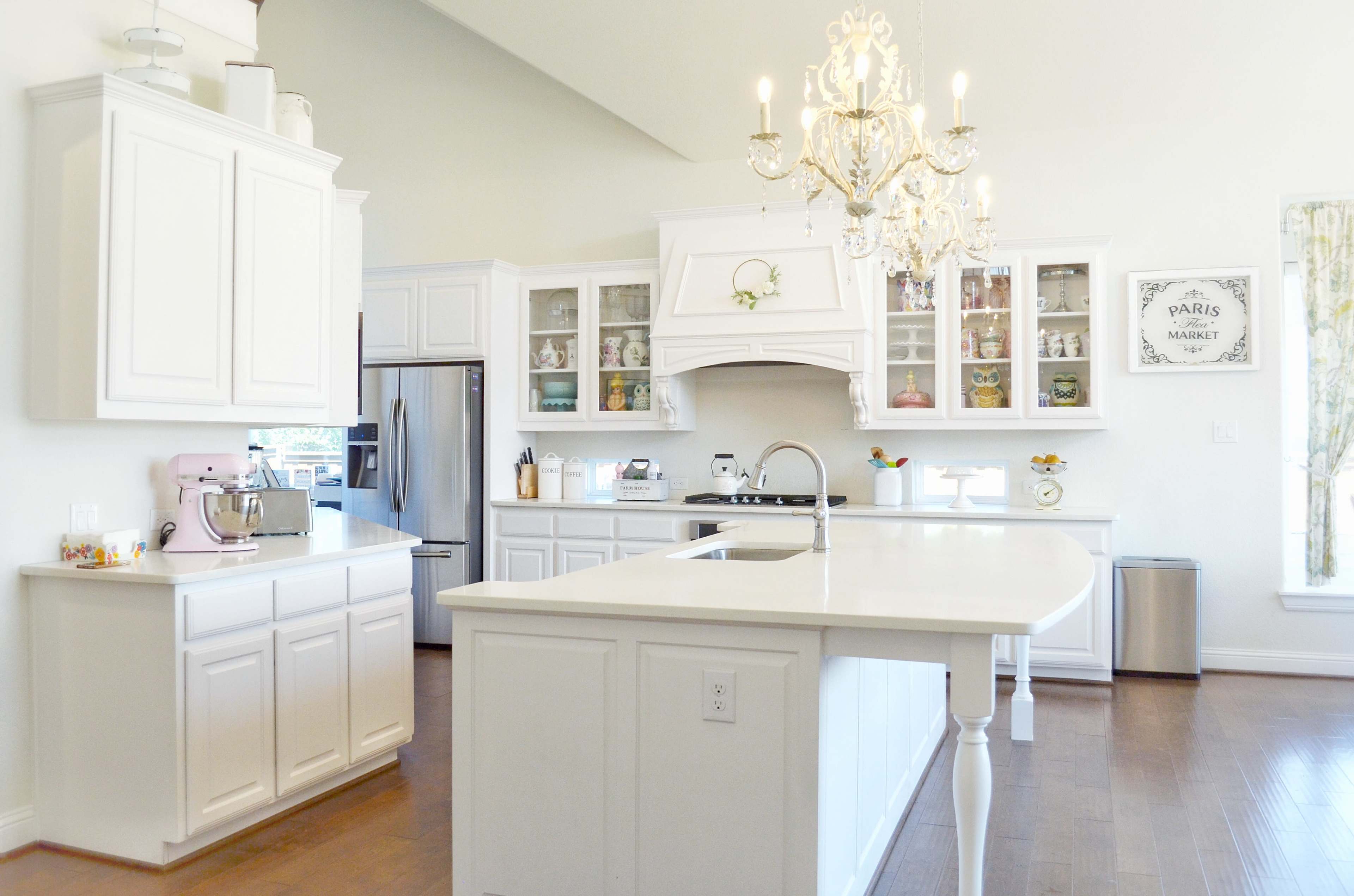 A bright, modern kitchen with white cabinetry, an island, and a chandelier.