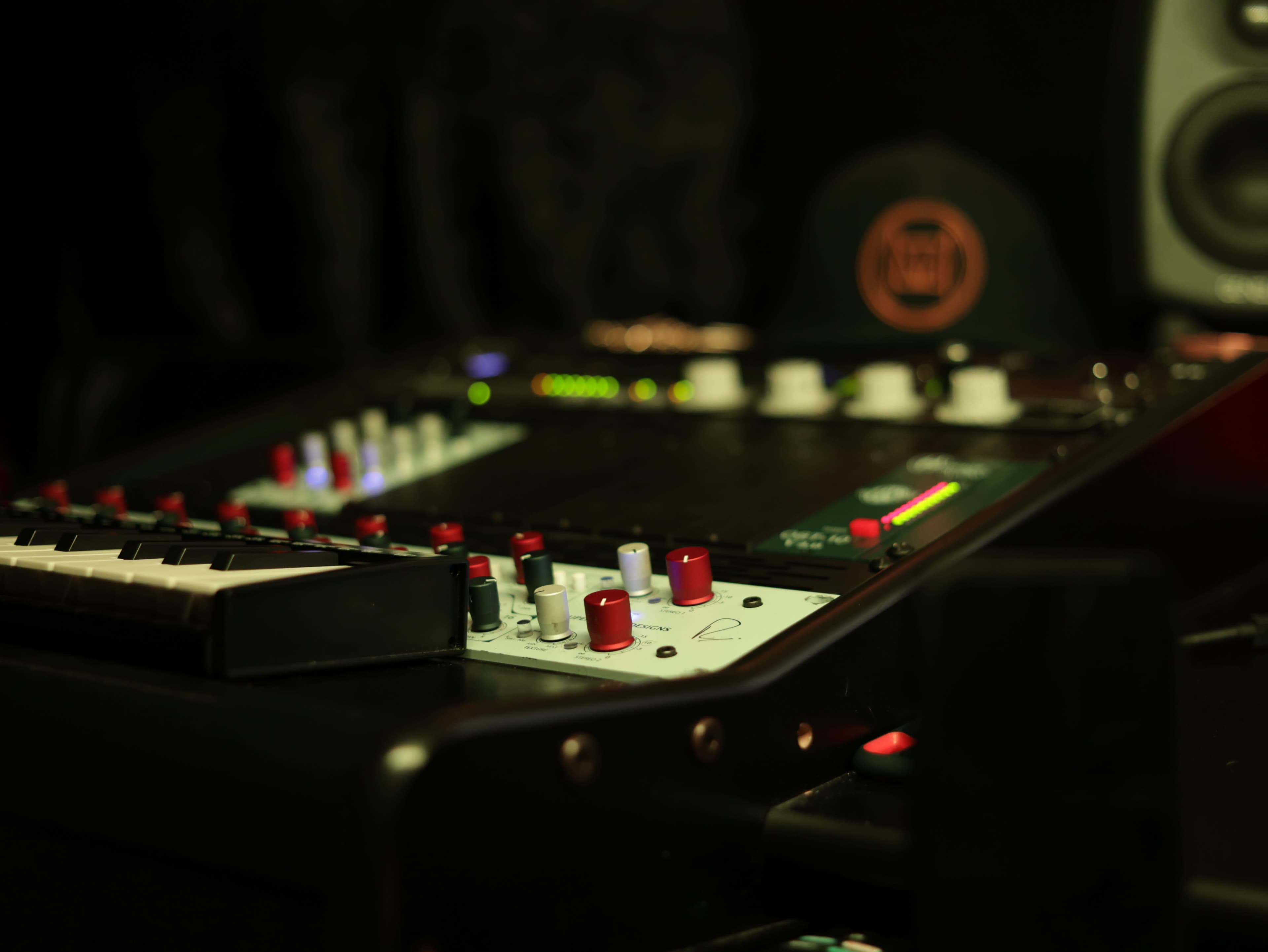 The image shows a close-up view of a music production interface with various knobs, buttons, and a keyboard element.
