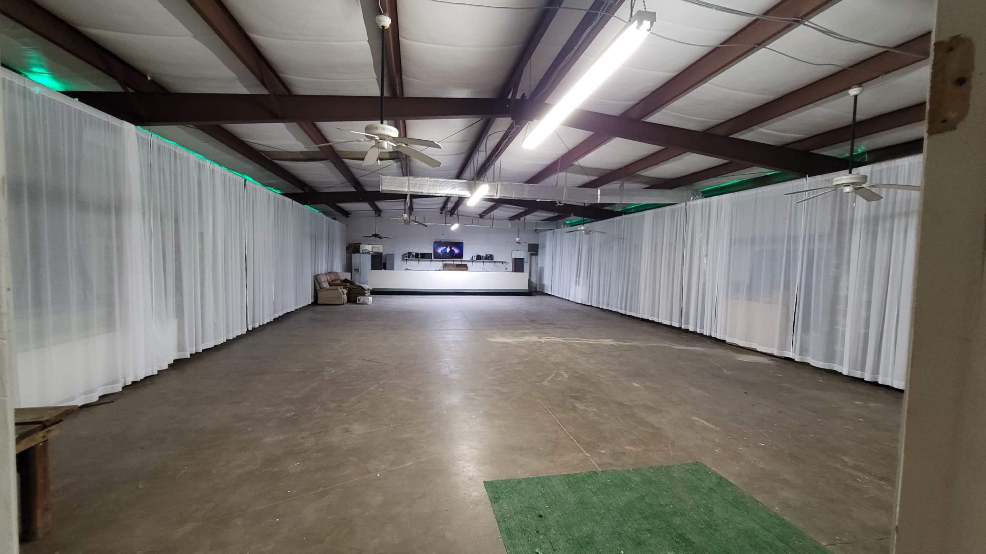 The spacious interior features a concrete floor, white curtains along the walls, and a service counter at the far end.