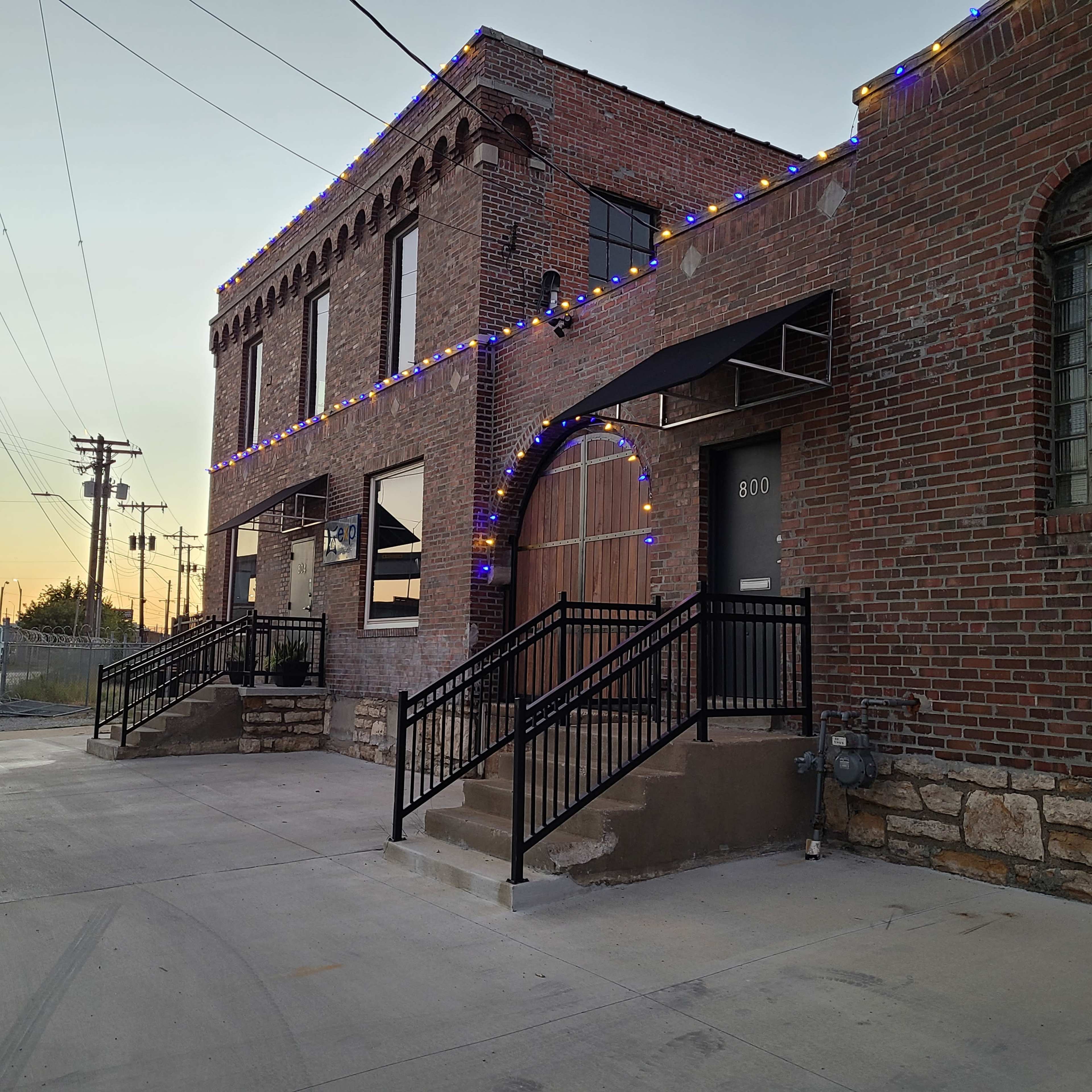 A two-story brick building with decorative lights along the top, featuring two staircases leading to the entrances.