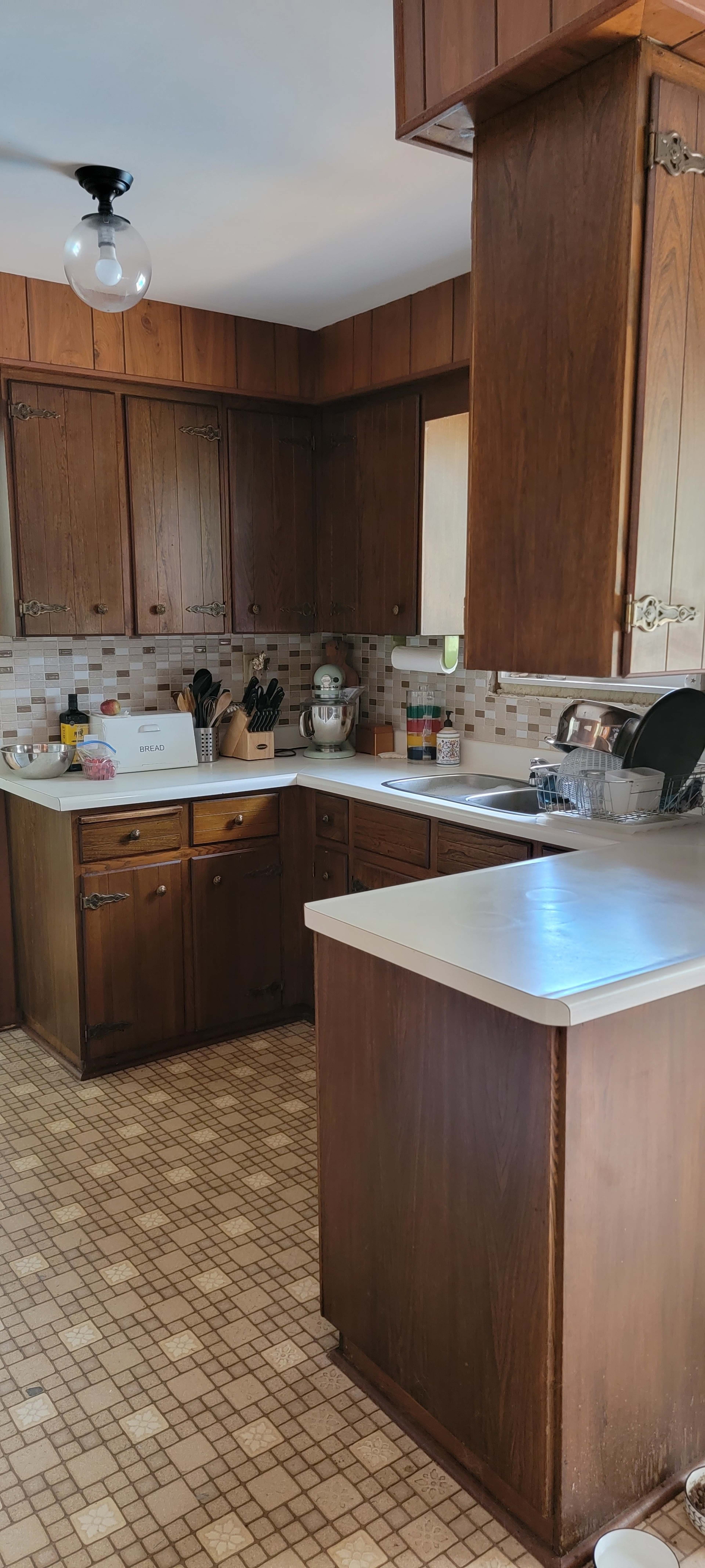 A kitchen with wooden cabinets, a countertop, and a checkered floor pattern.