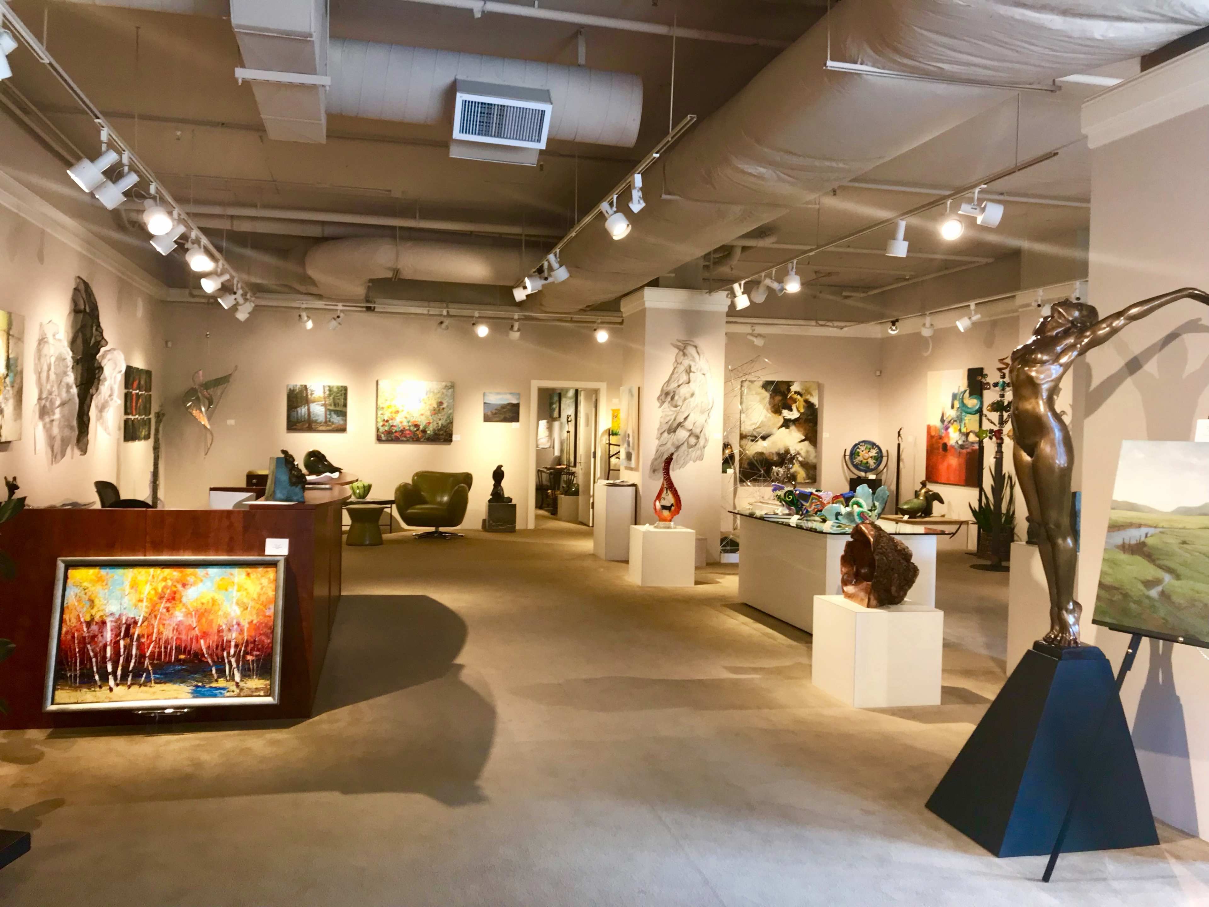 A spacious art gallery featuring various paintings, sculptures, and decorative pieces displayed throughout the room.