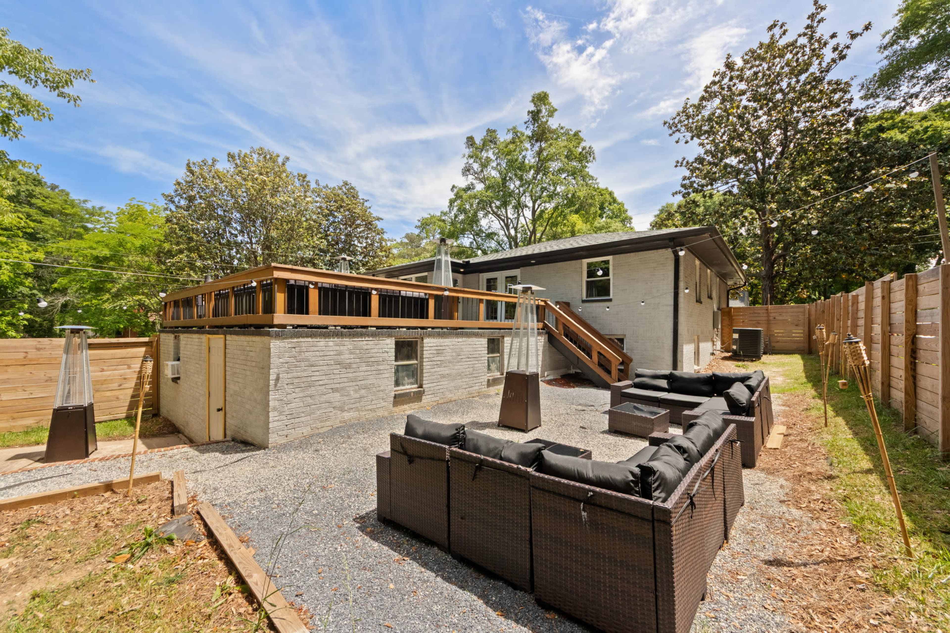The image shows a modern backyard with a gravel area, outdoor seating set, and a building with a wooden deck.
