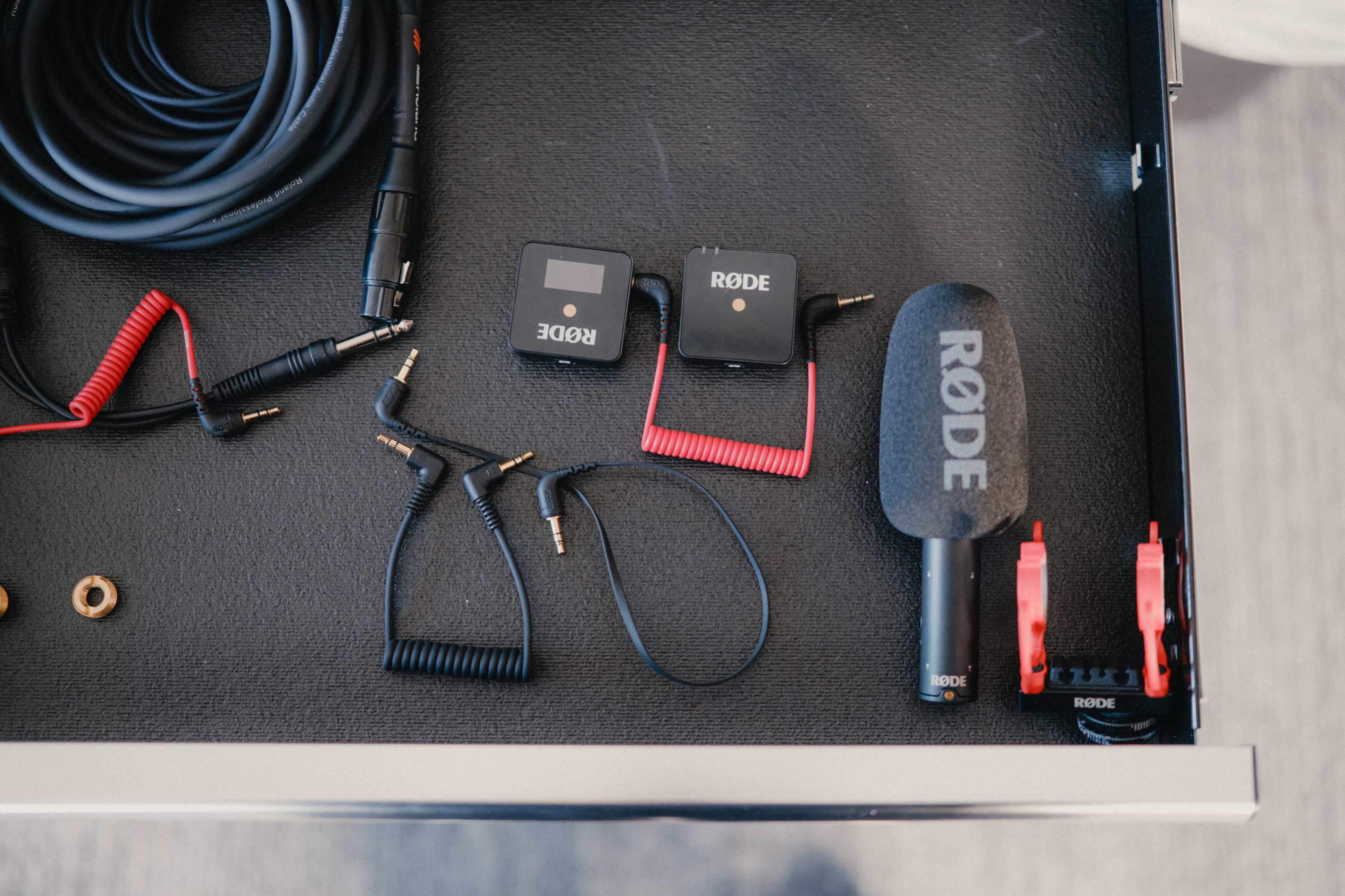 The image shows various audio equipment, including a microphone, cables, and adapters organized in a drawer.