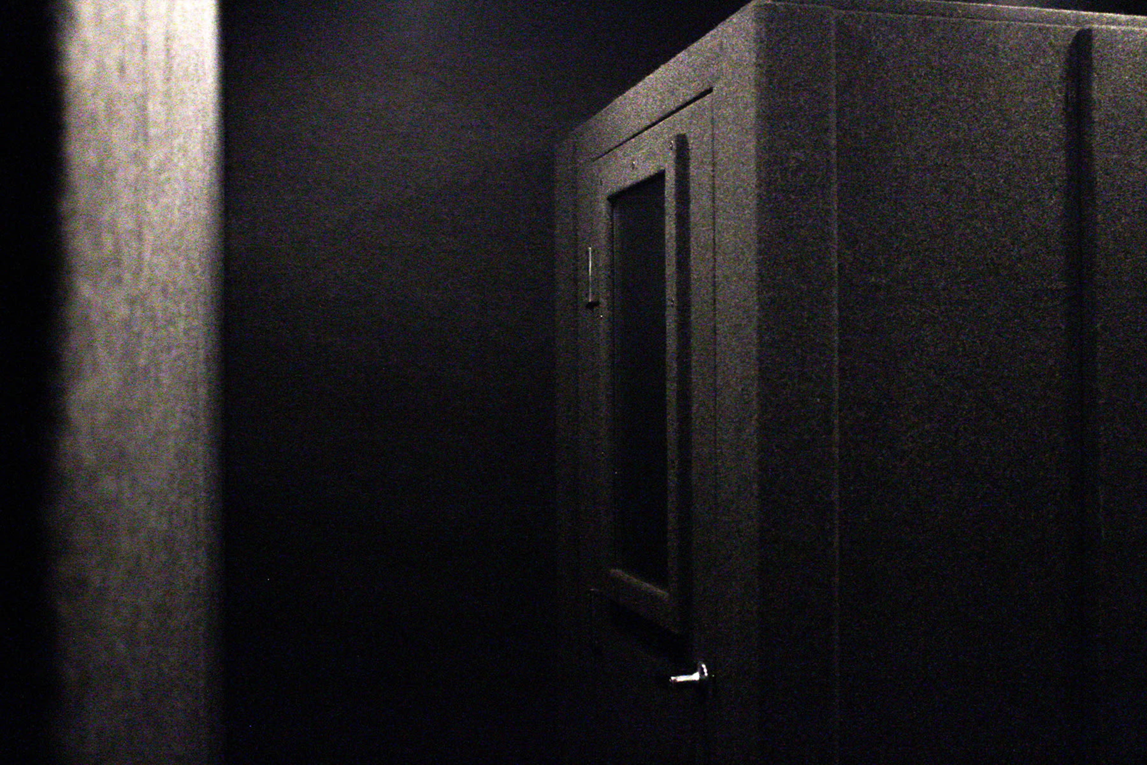 A dark, soundproof booth with a small window located in a dimly lit space.