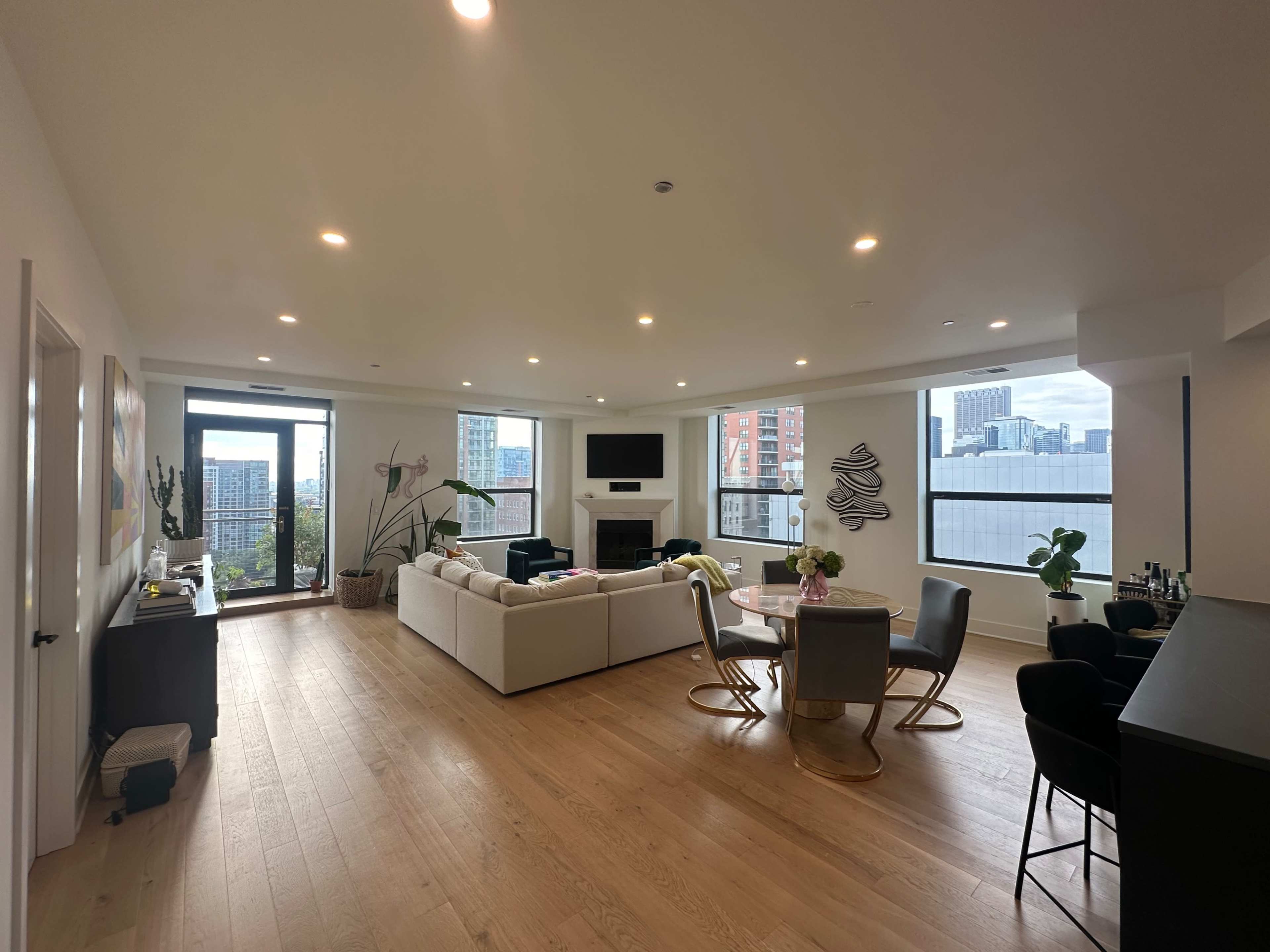 A modern, open-concept living and dining area with large windows offering a city view.