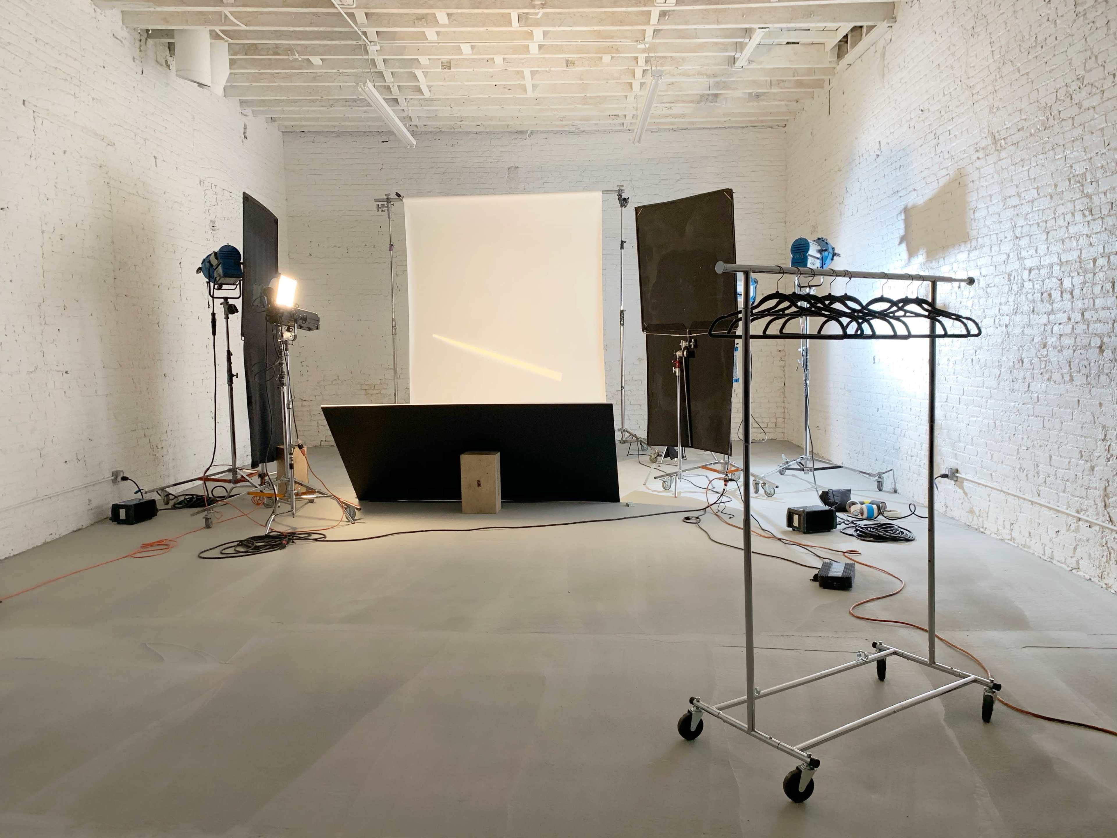A photography studio with a light setup, backdrop, and a clothing rack on wheels.