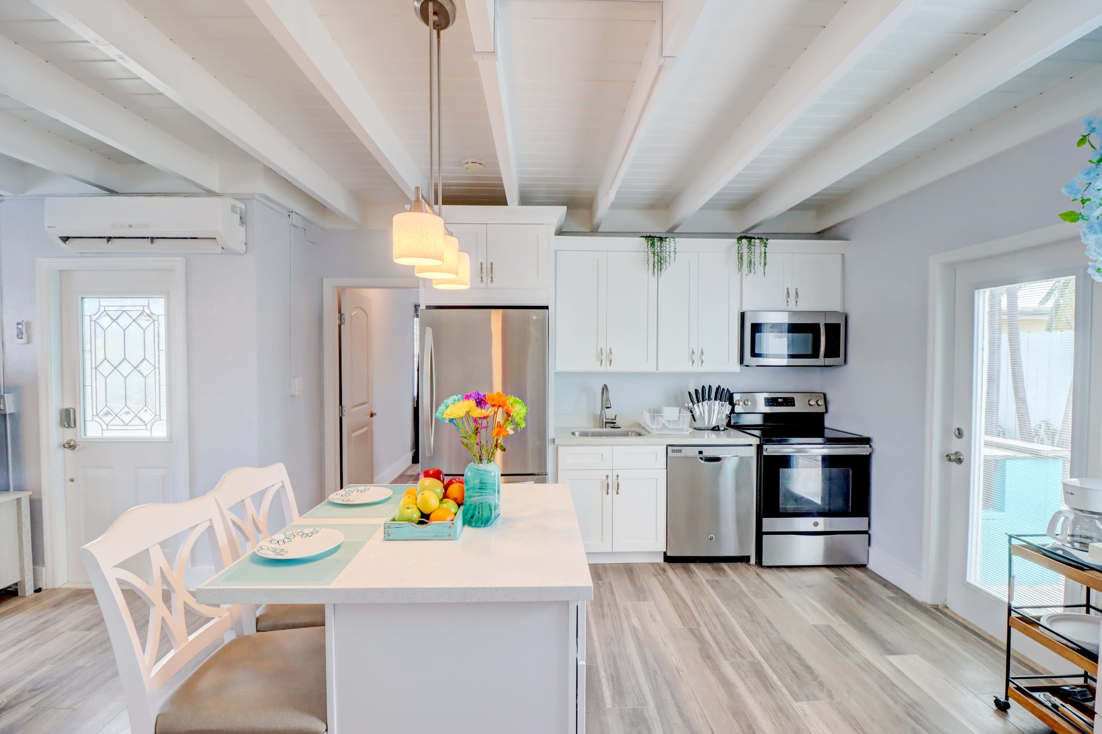 A modern kitchen features white cabinets, stainless steel appliances, a central island with seating, and a bright blue and white color scheme.