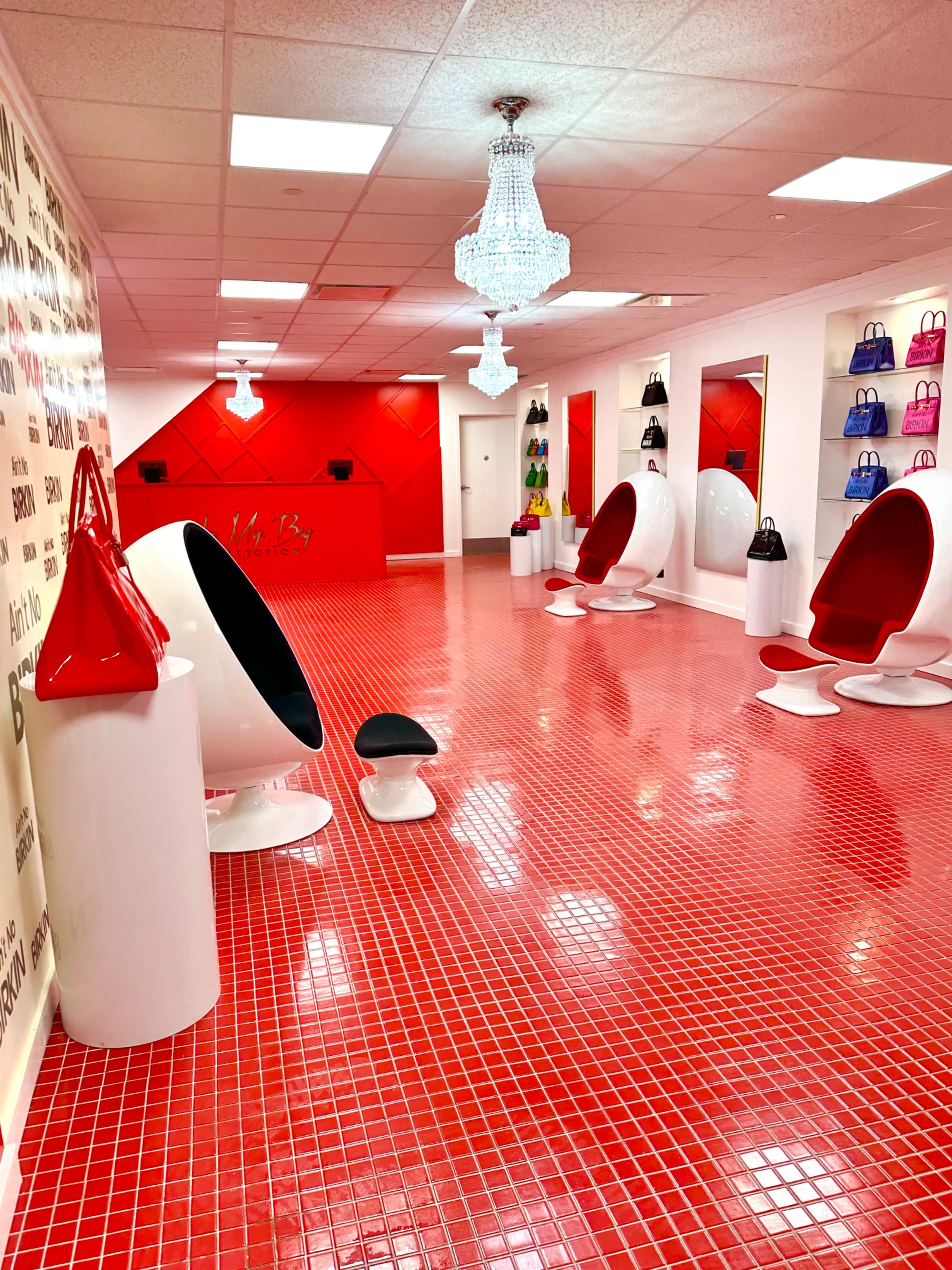 A modern boutique interior with red tile flooring, white furniture, and colorful handbags displayed on the walls.