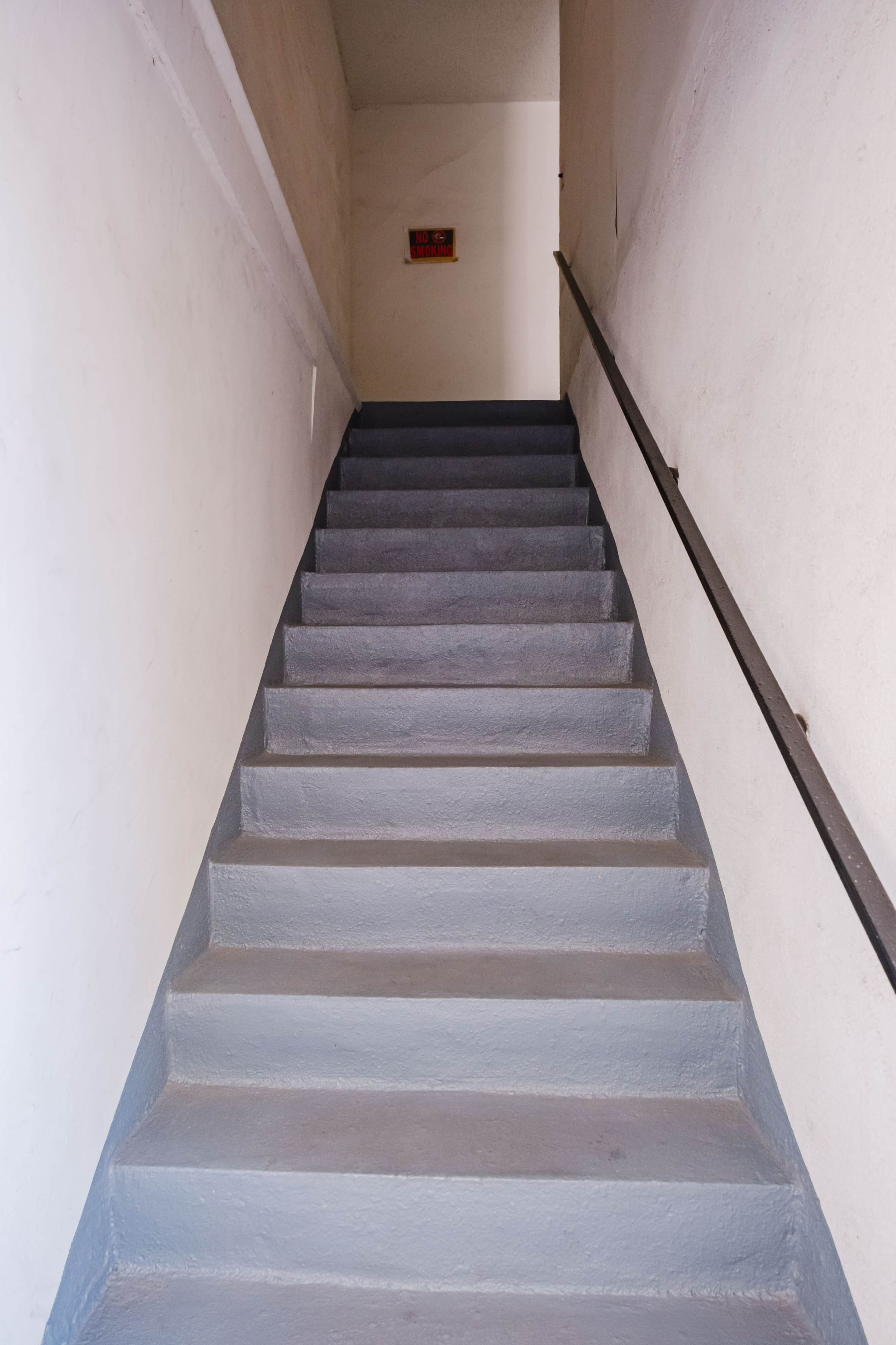 A set of gray stairs leads up to a door at the top, with a handrail on the right side.
