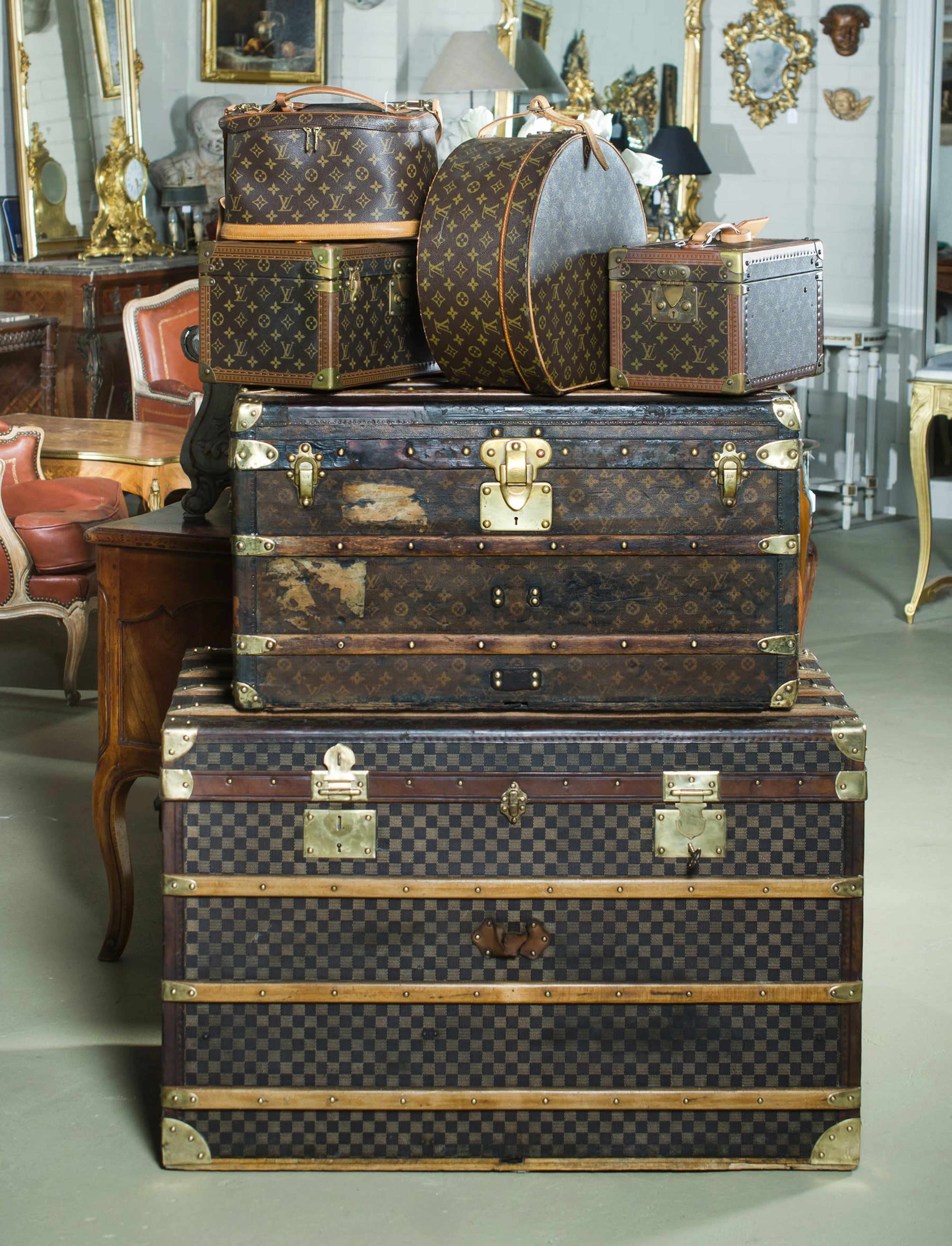 A stack of vintage Louis Vuitton suitcases and trunks placed in a well-decorated interior space.
