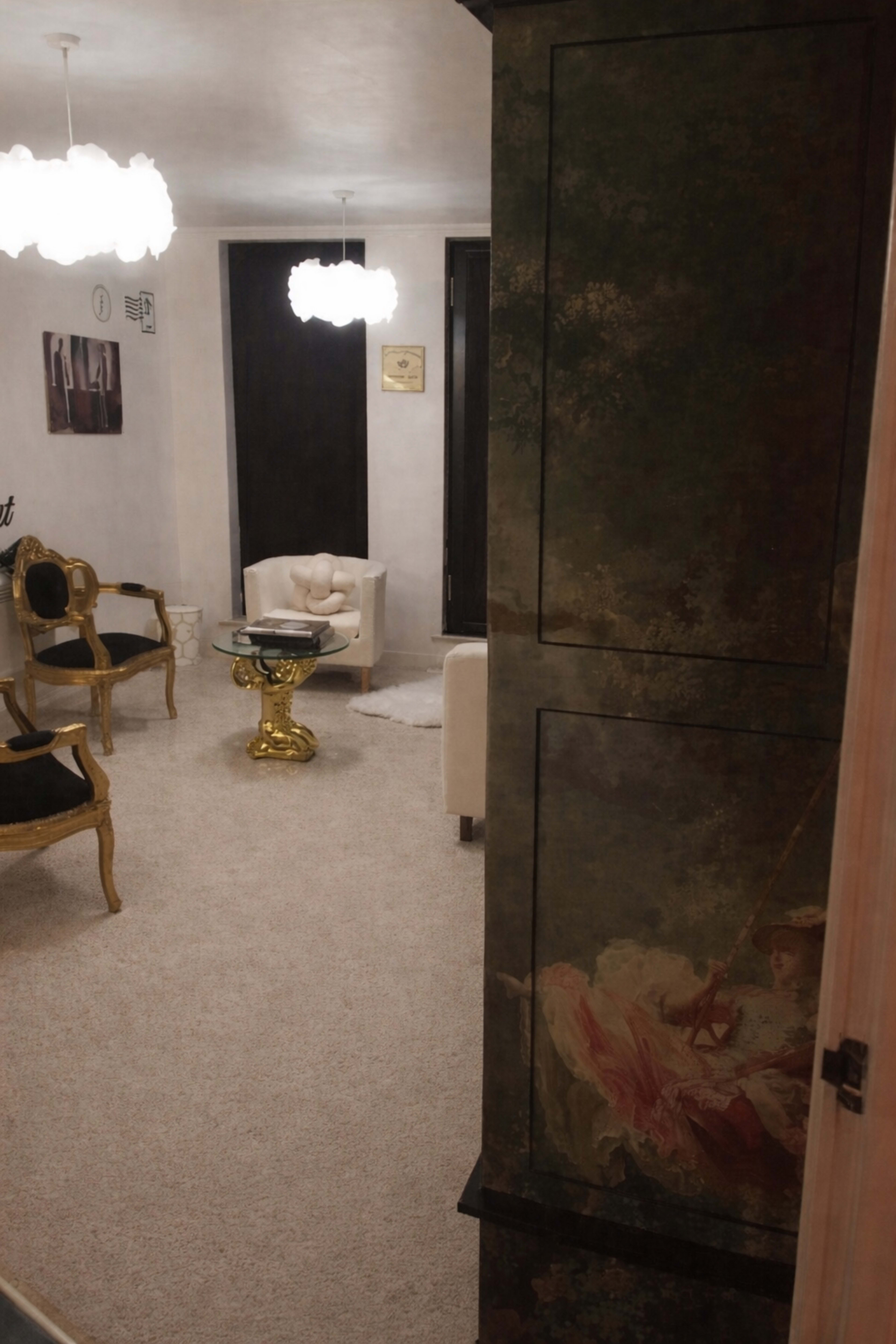 The image shows a softly lit living room featuring plush furniture, a decorative cabinet, and modern light fixtures.