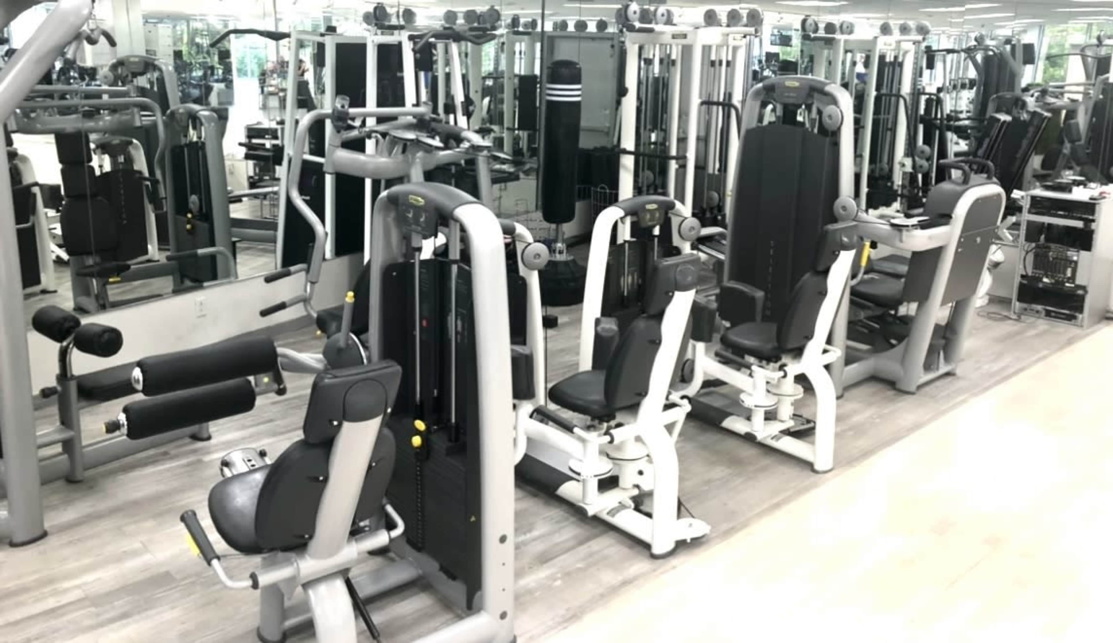 A gym interior with several weight training machines arranged in a mirrored space.