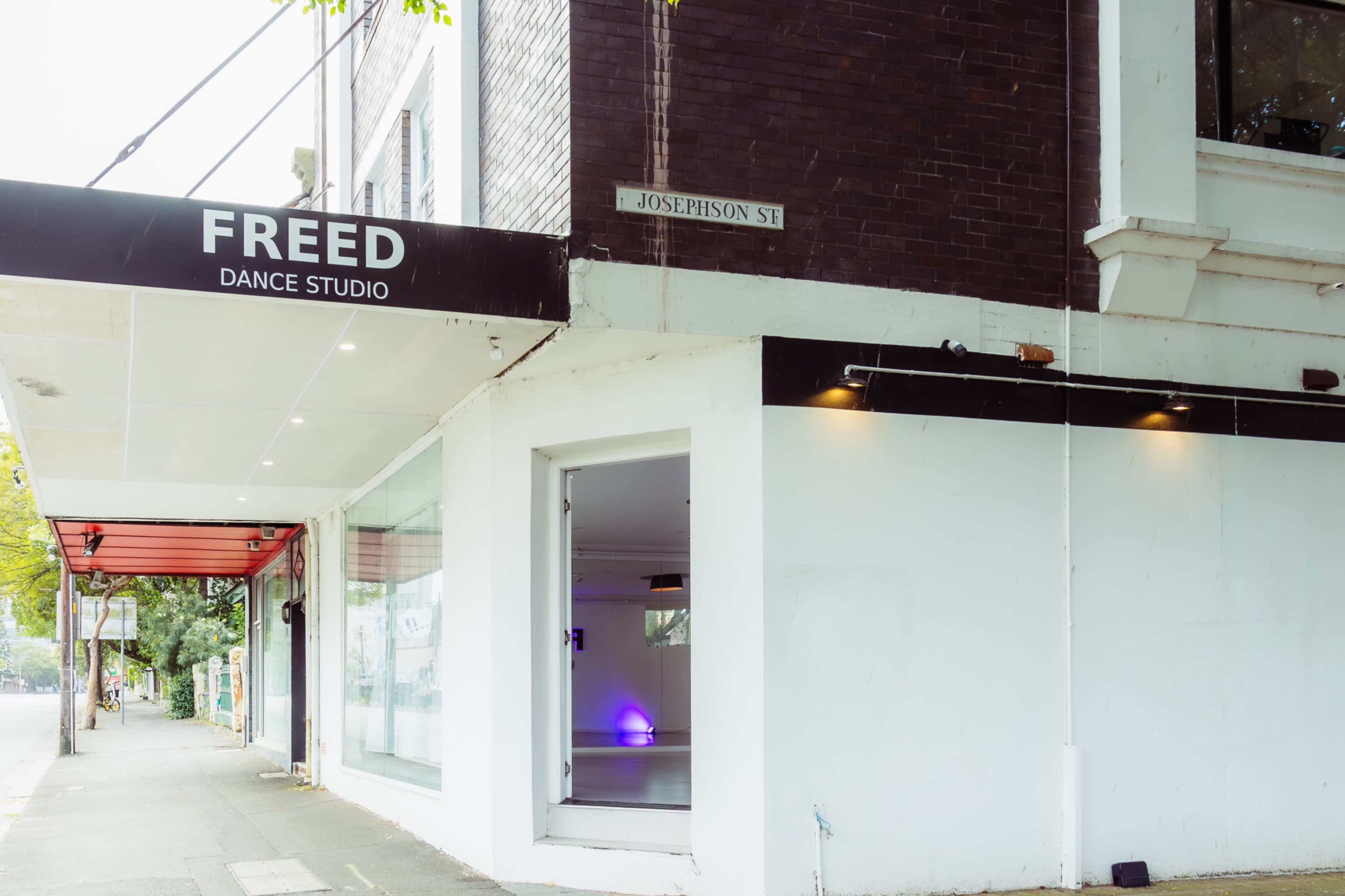 The image shows the exterior of the Freed Dance Studio, featuring a sign above a white entrance and a street sign for Josephson Street.