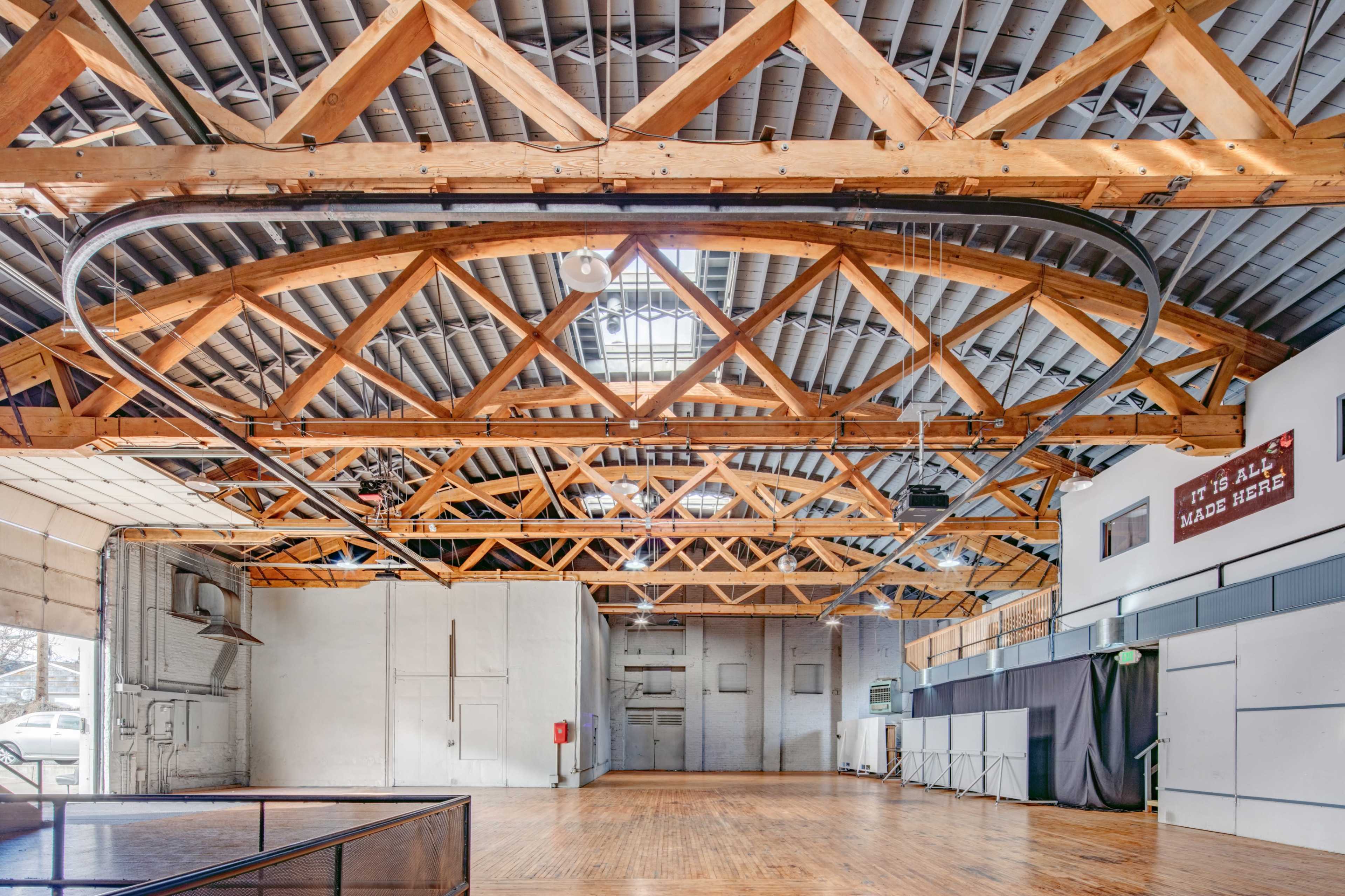 A spacious indoor venue with wooden beams, high ceilings, and a polished wooden floor.