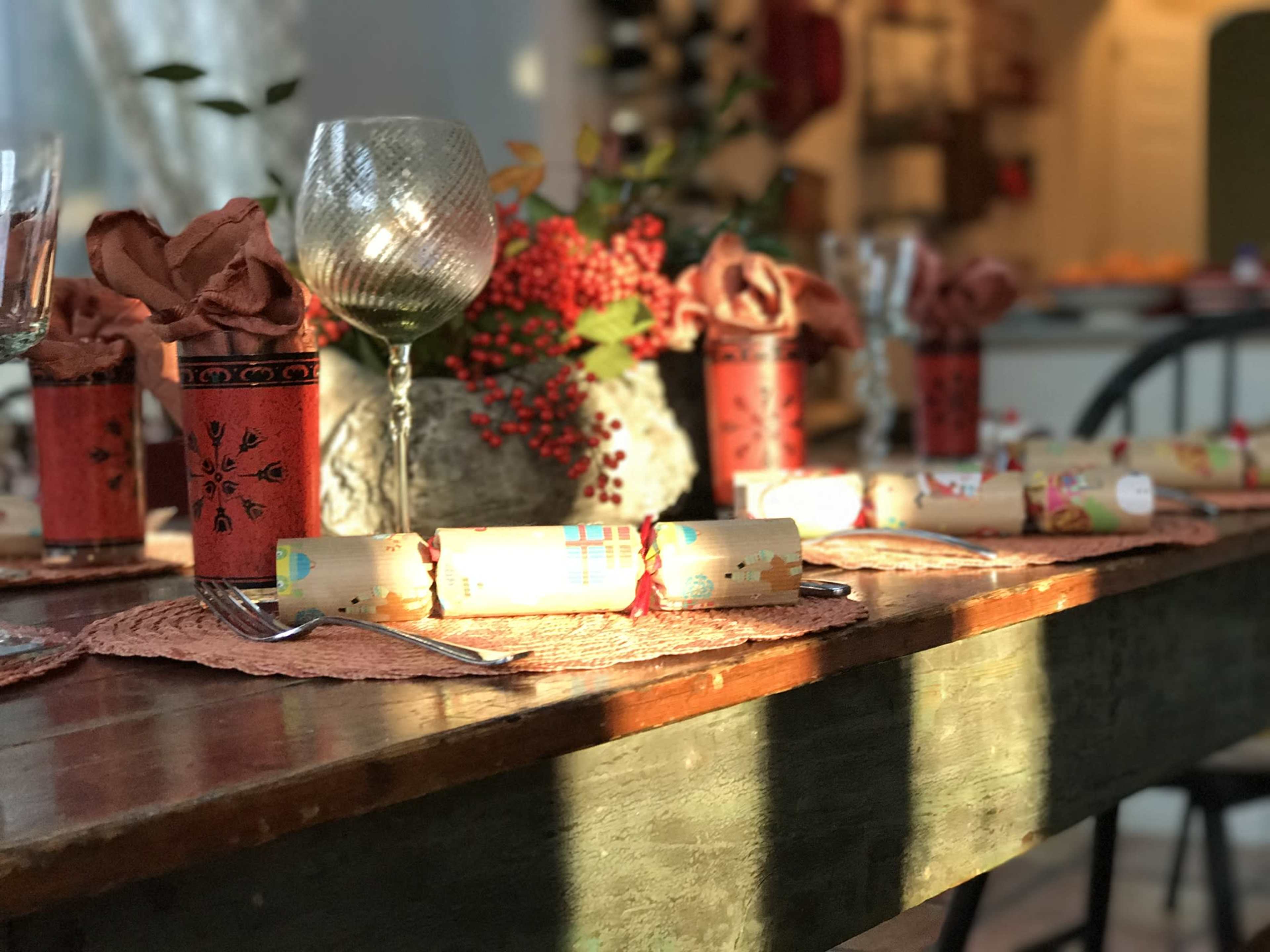 A dining table is set with decorated napkins, festive party favors, and glasses, surrounded by a cozy, warmly lit interior.