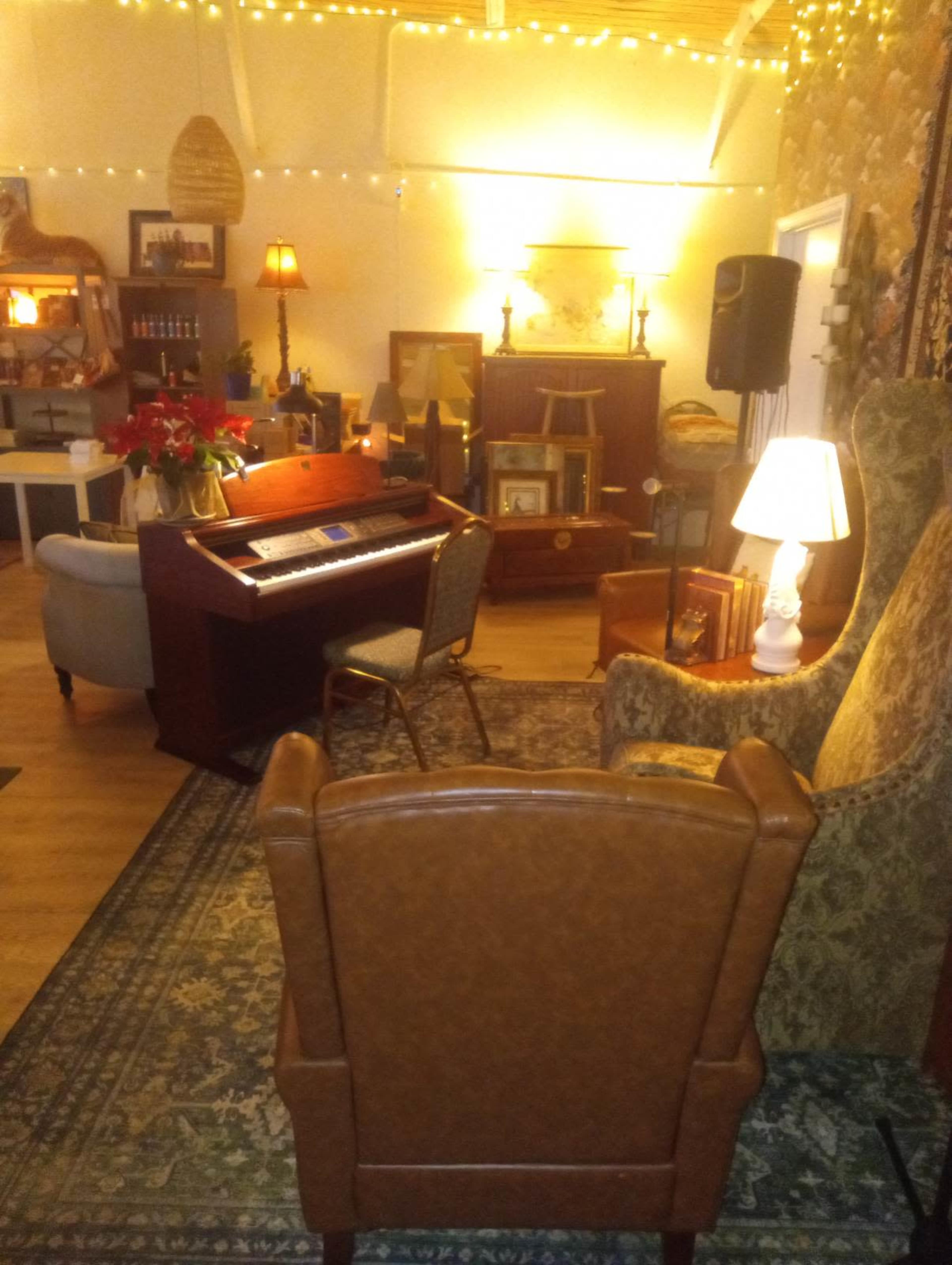The image shows a cozy interior with a piano, comfortable seating, and softly lit decor, creating a warm atmosphere.