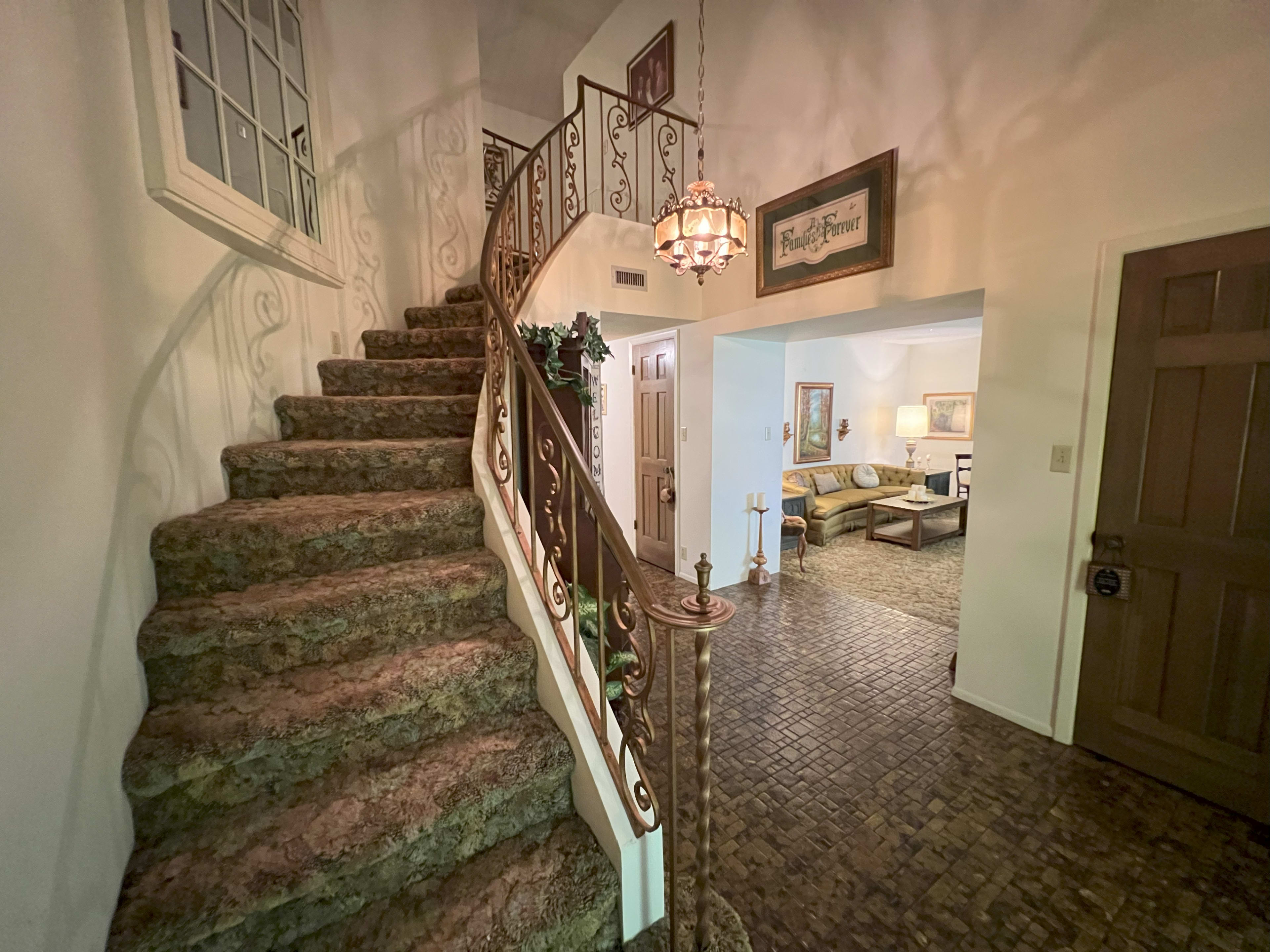 A spiral staircase with a decorative railing leads to an upper floor, and a living area is visible in the background.