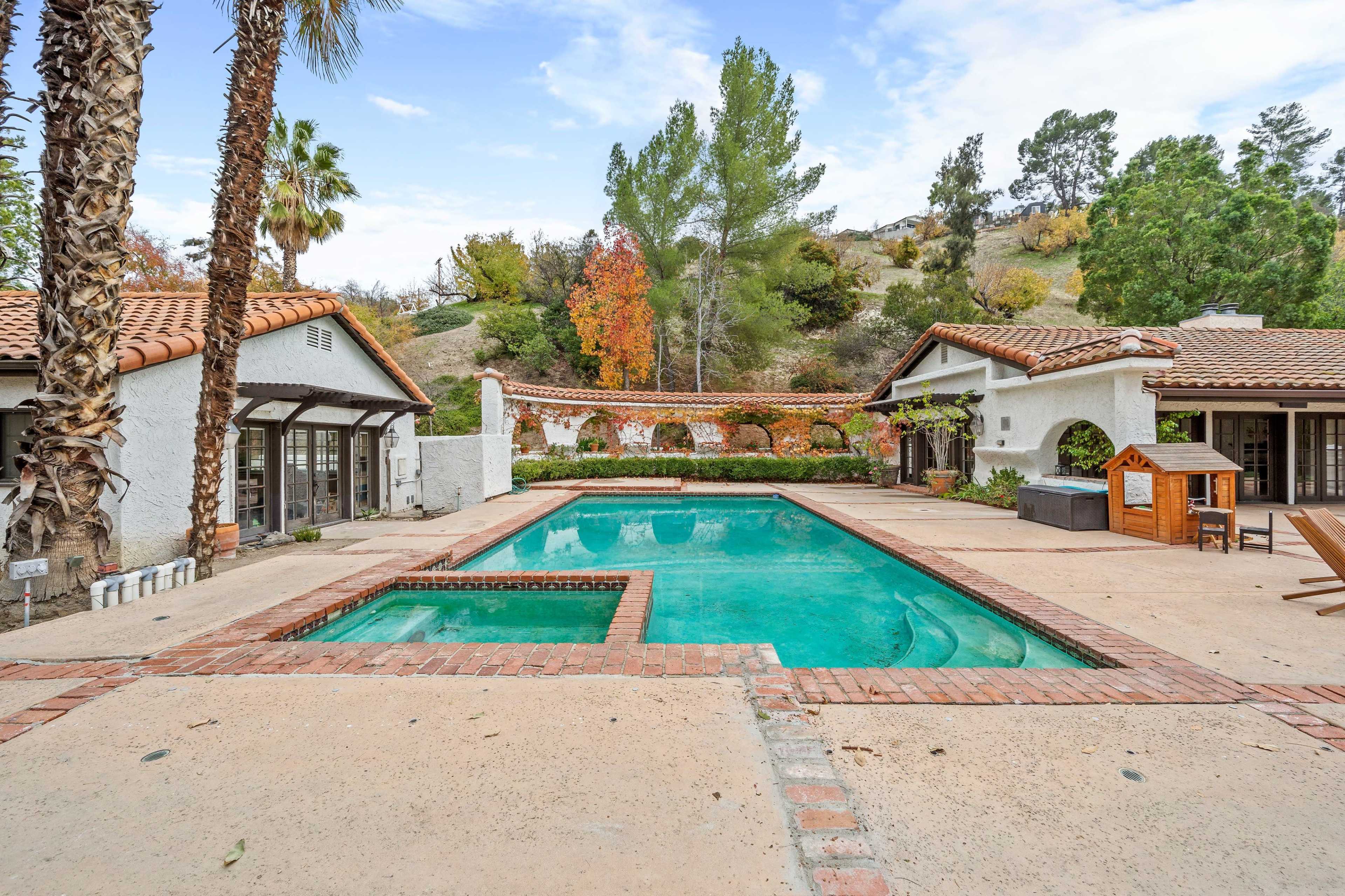 A spacious outdoor area with a swimming pool surrounded by palm trees and residential buildings.