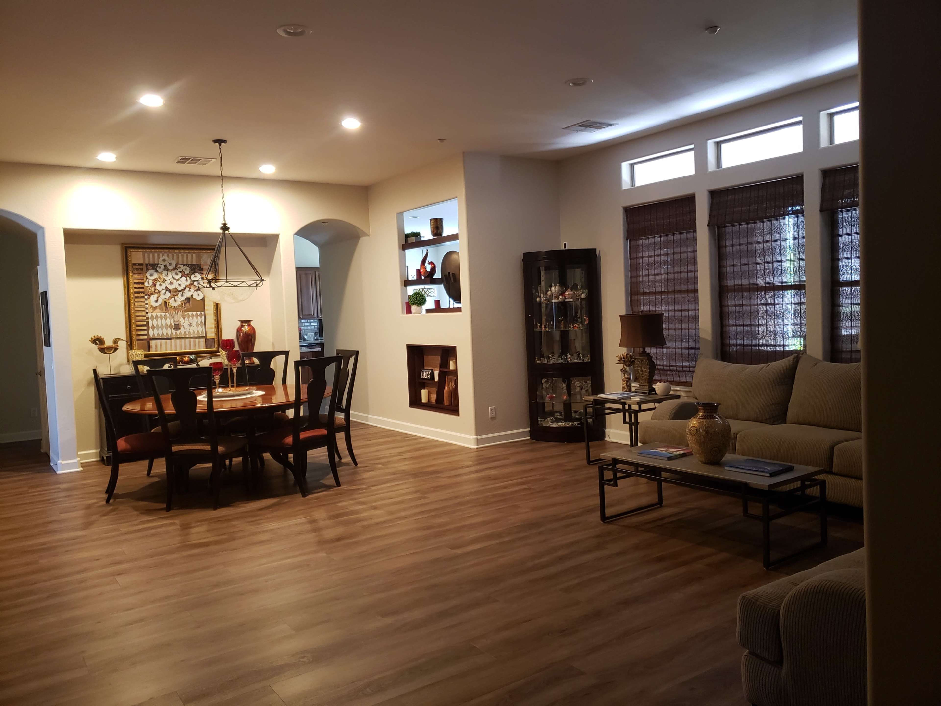 A modern living room and dining area with wood flooring, a round dining table, and a comfortable sofa.