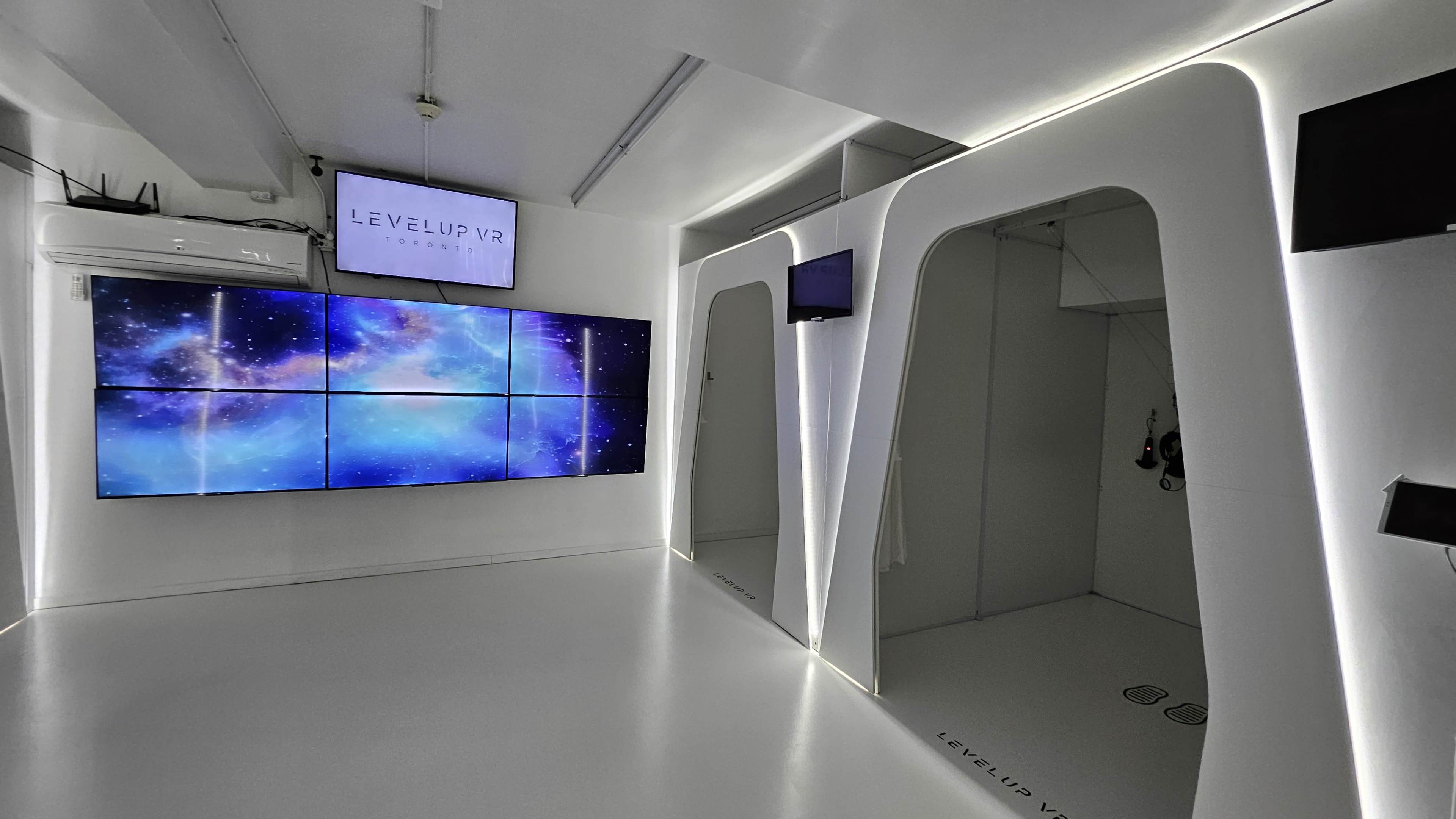 The image shows a modern room featuring a large wall of screens displaying a cosmic graphic, with sleek, white walls and minimalistic design elements.